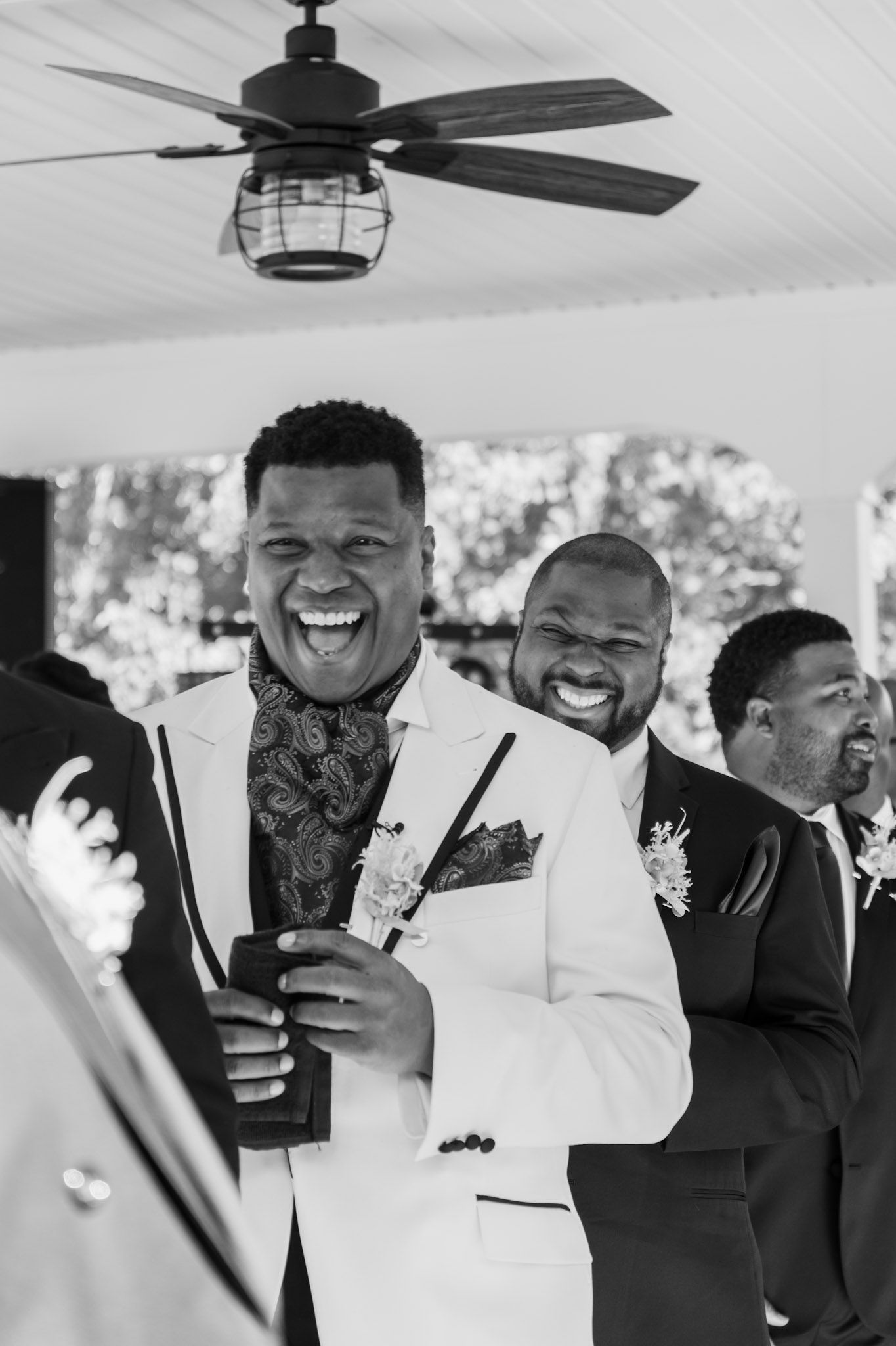 Wedding party members sharing a joyful moment under a ceiling fan.
