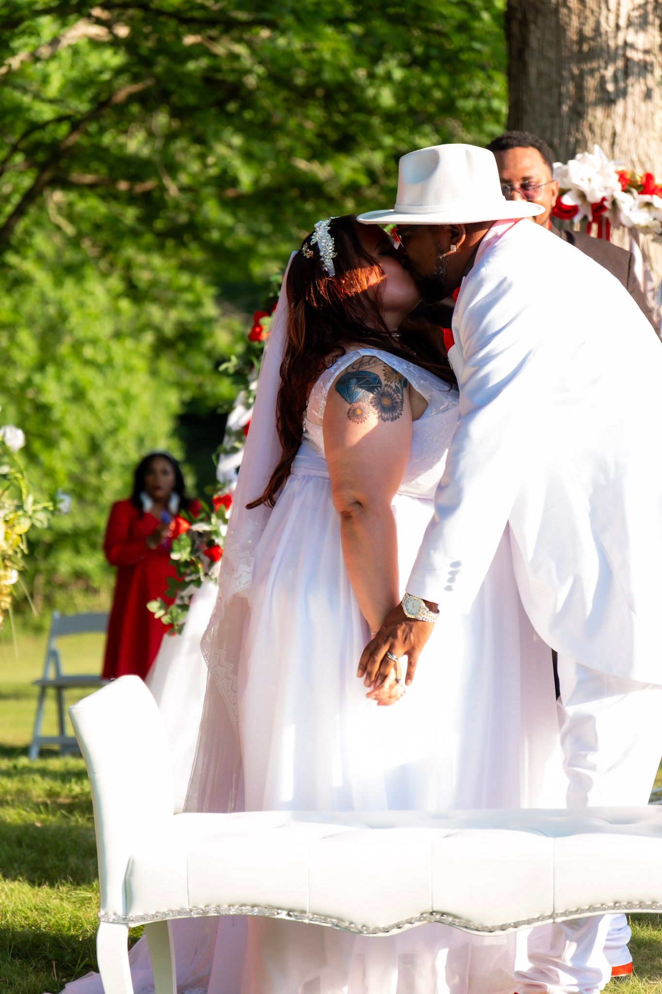 Couple sharing an intimate kiss during their wedding ceremony in a garden setting.