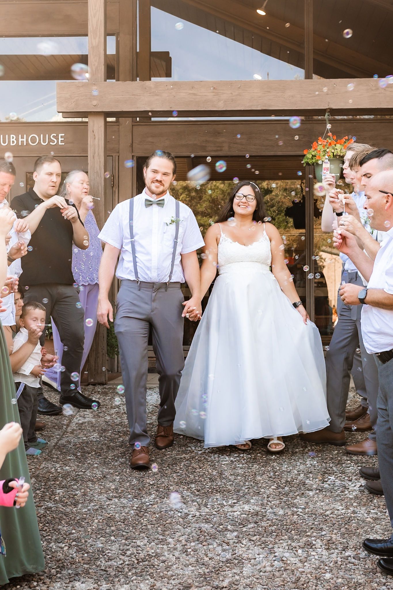 Wedding guests blow bubbles as newlyweds exit the clubhouse after their ceremony.