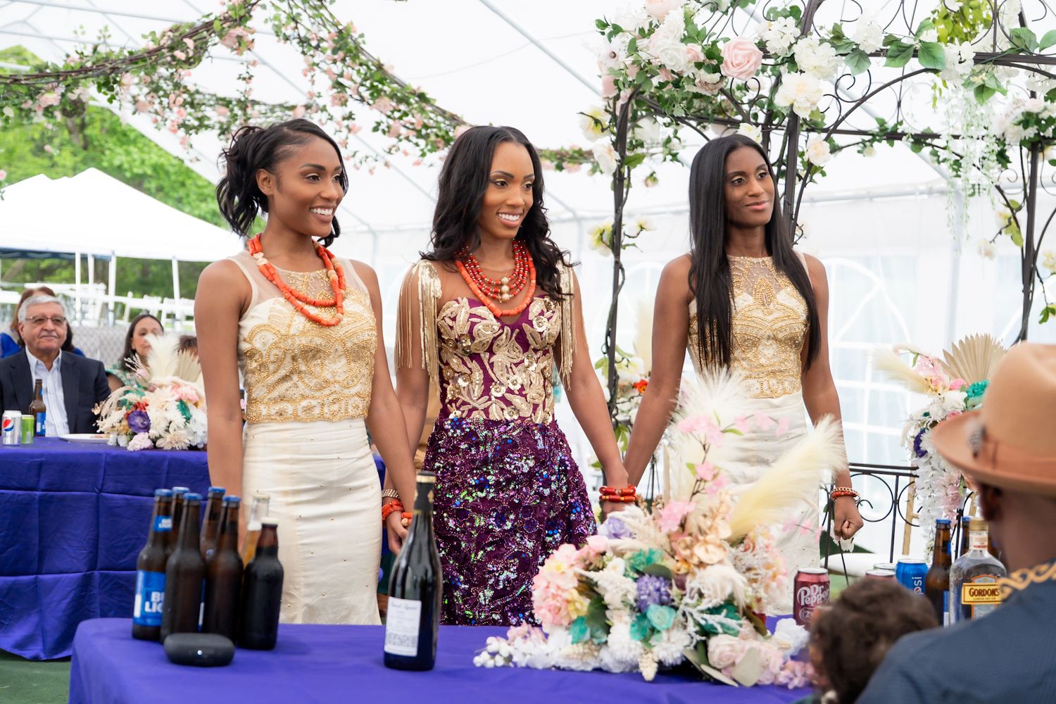 Wedding celebration with guests enjoying champagne under floral-decorated tent.