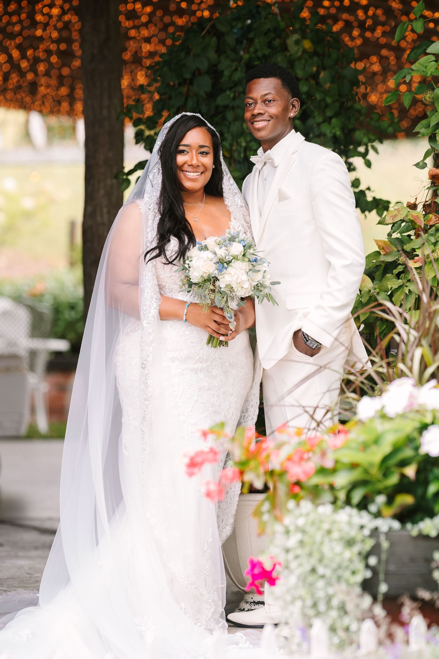 A wedding portrait with floral decorations and orange lights creating a romantic outdoor atmosphere.