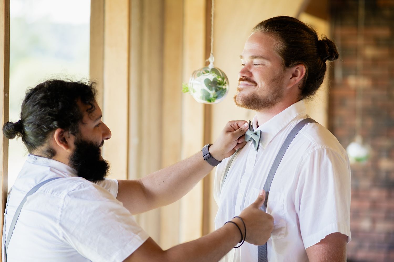 A bow tie adjustment captured during wedding preparations on a porch.
