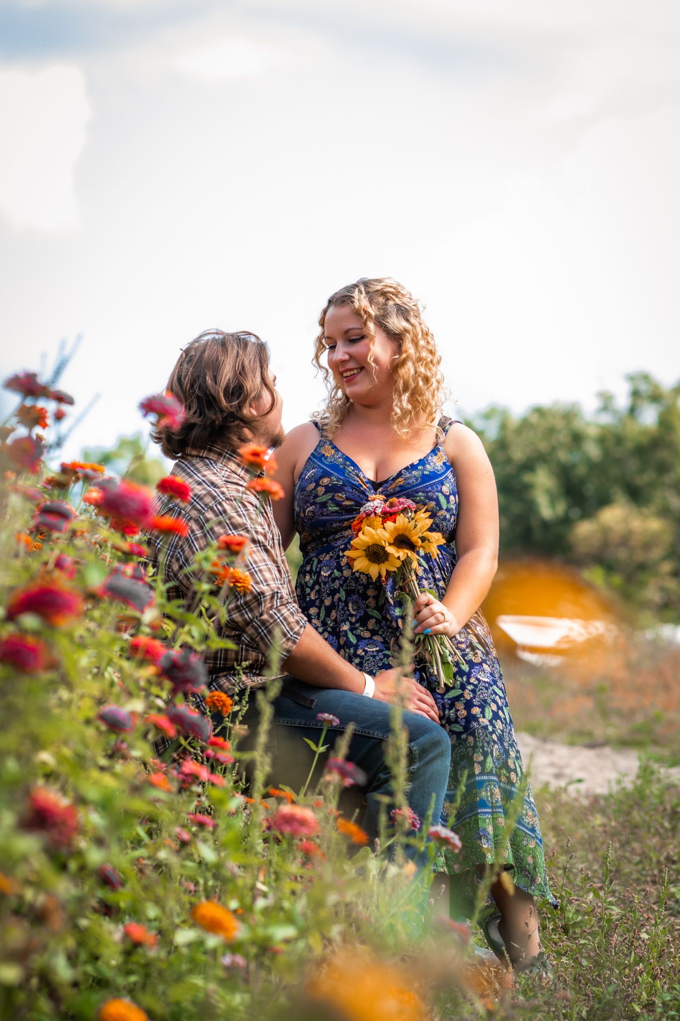 A couple embraces among red and orange wildflowers on a bright summer day.
