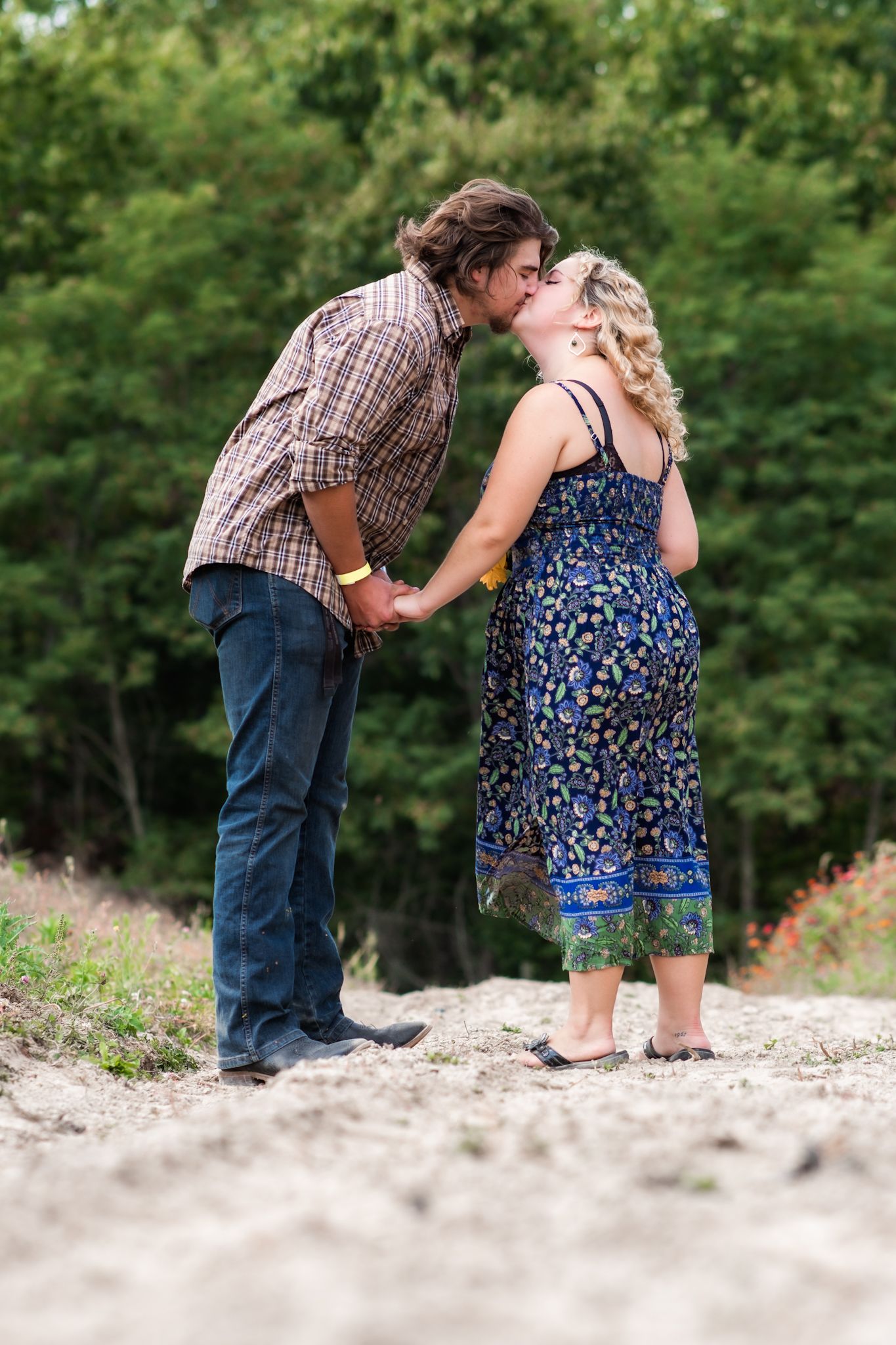 A romantic moment between two people in blue and plaid attire against a lush natural background.