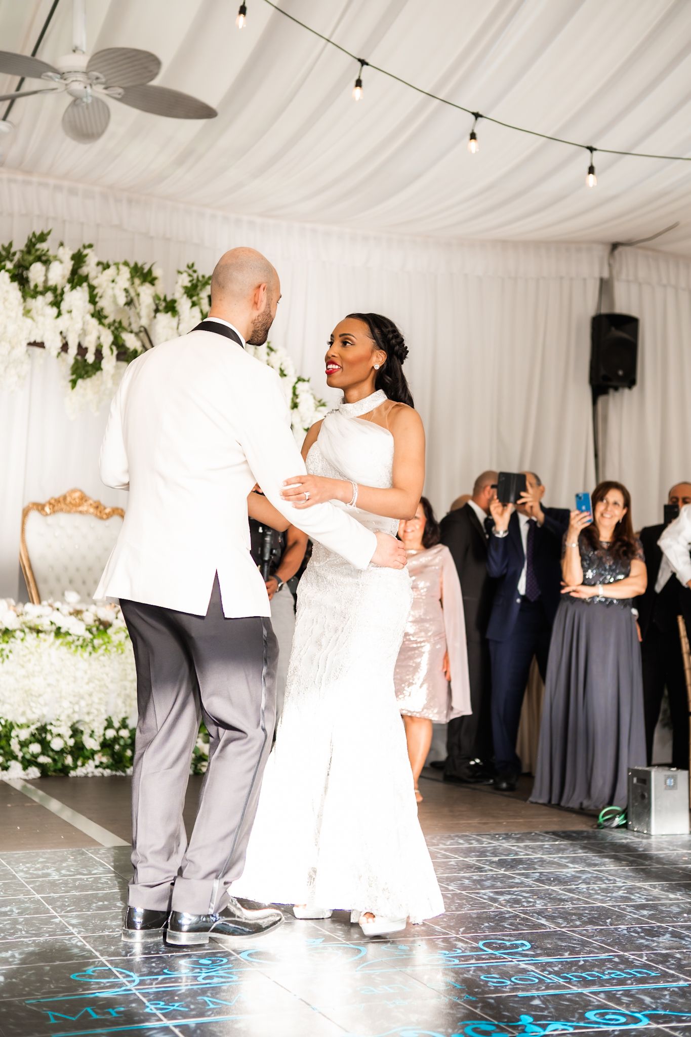 Newlyweds sharing their first dance in an elegantly decorated reception tent.