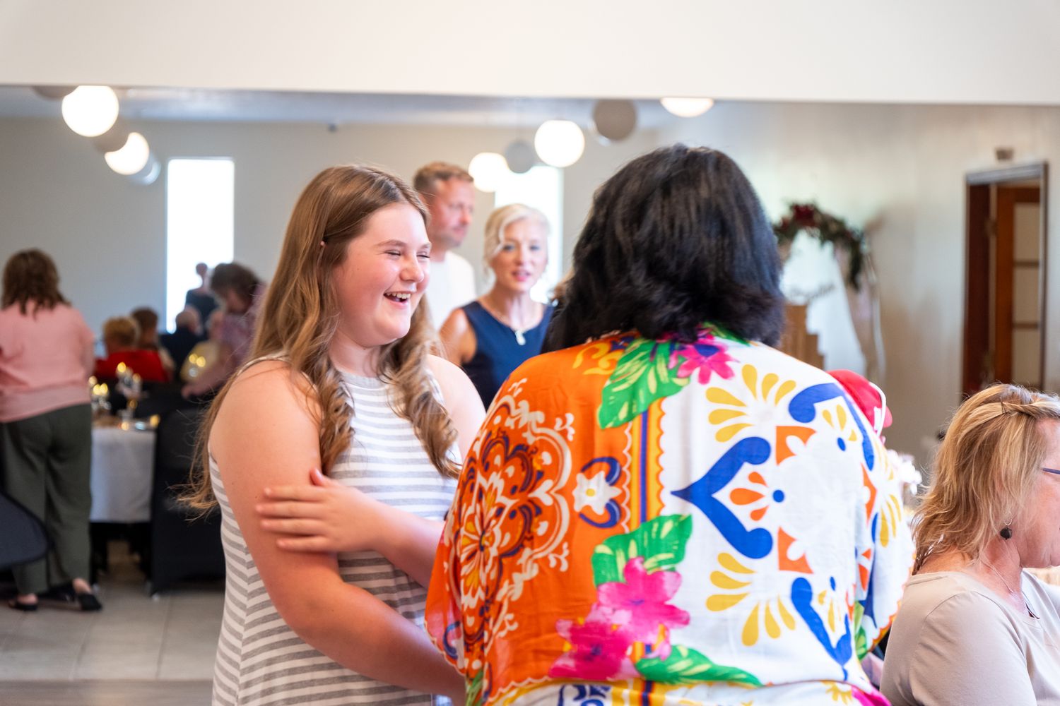 A collage of celebratory moments at an indoor event with people socializing, dancing and embracing in a bright setting.
