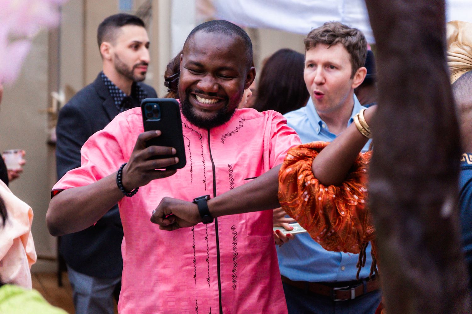 Joyful guest in pink shirt looking at phone during celebratory event.