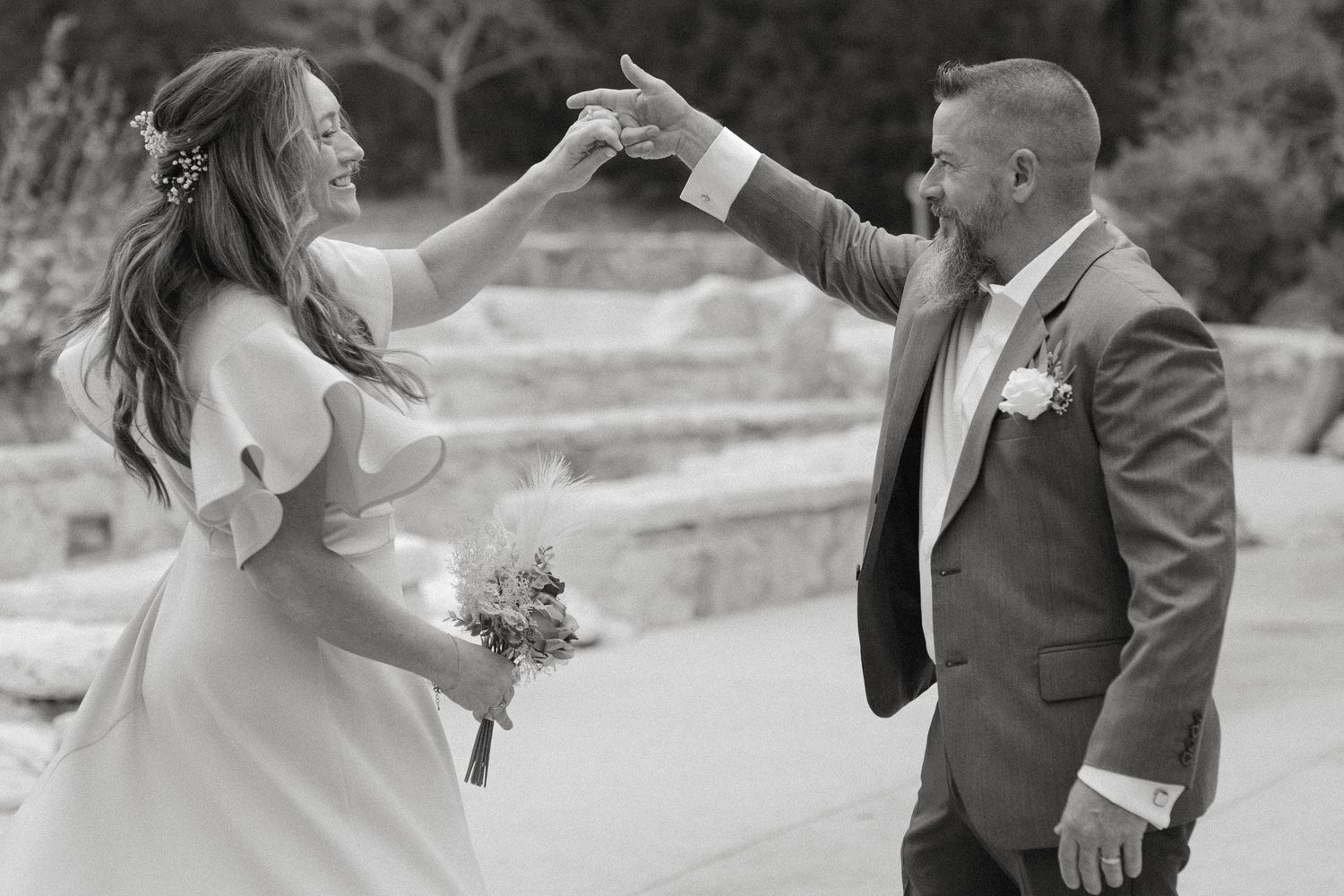 Candid black and white wedding photography of a bride holding a bouquet while being twirled by her groom during their first dance