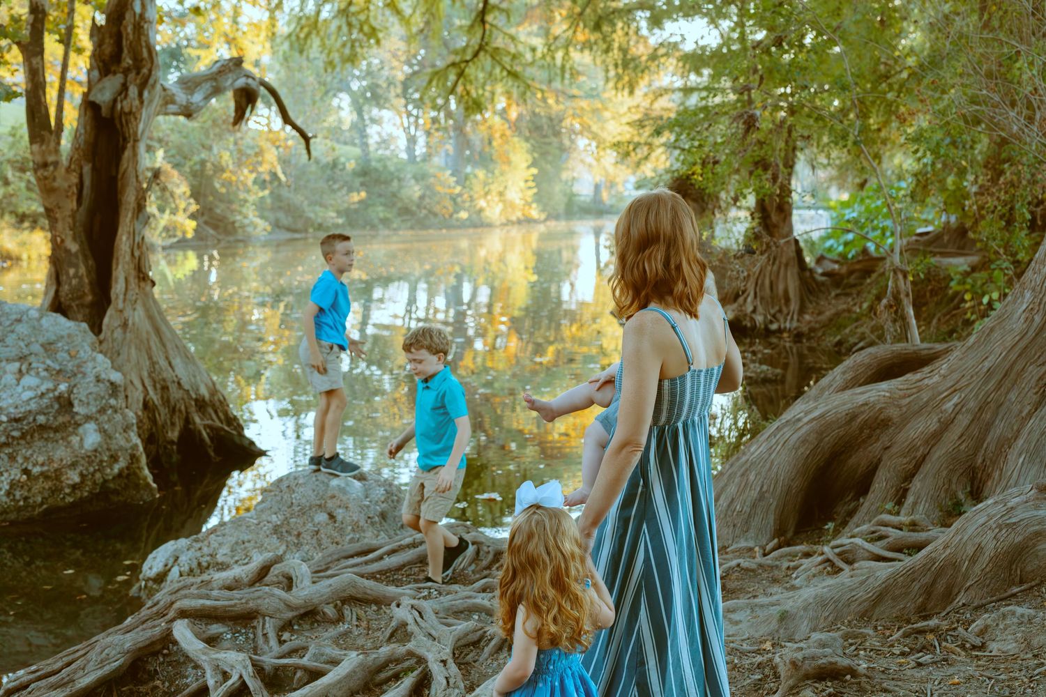 A mother and her children exploring the scenic, tree-lined riverbank of the Guadalupe River in Central Texas.