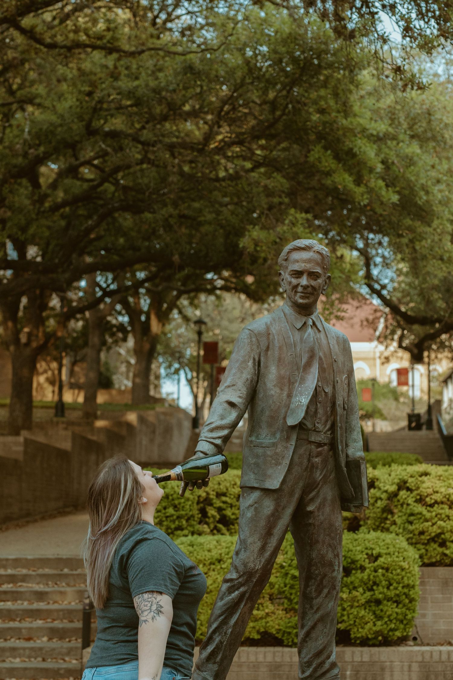Texas State University graduate posing playfully with the LBJ statue during a senior photo session in San Marcos, TX.