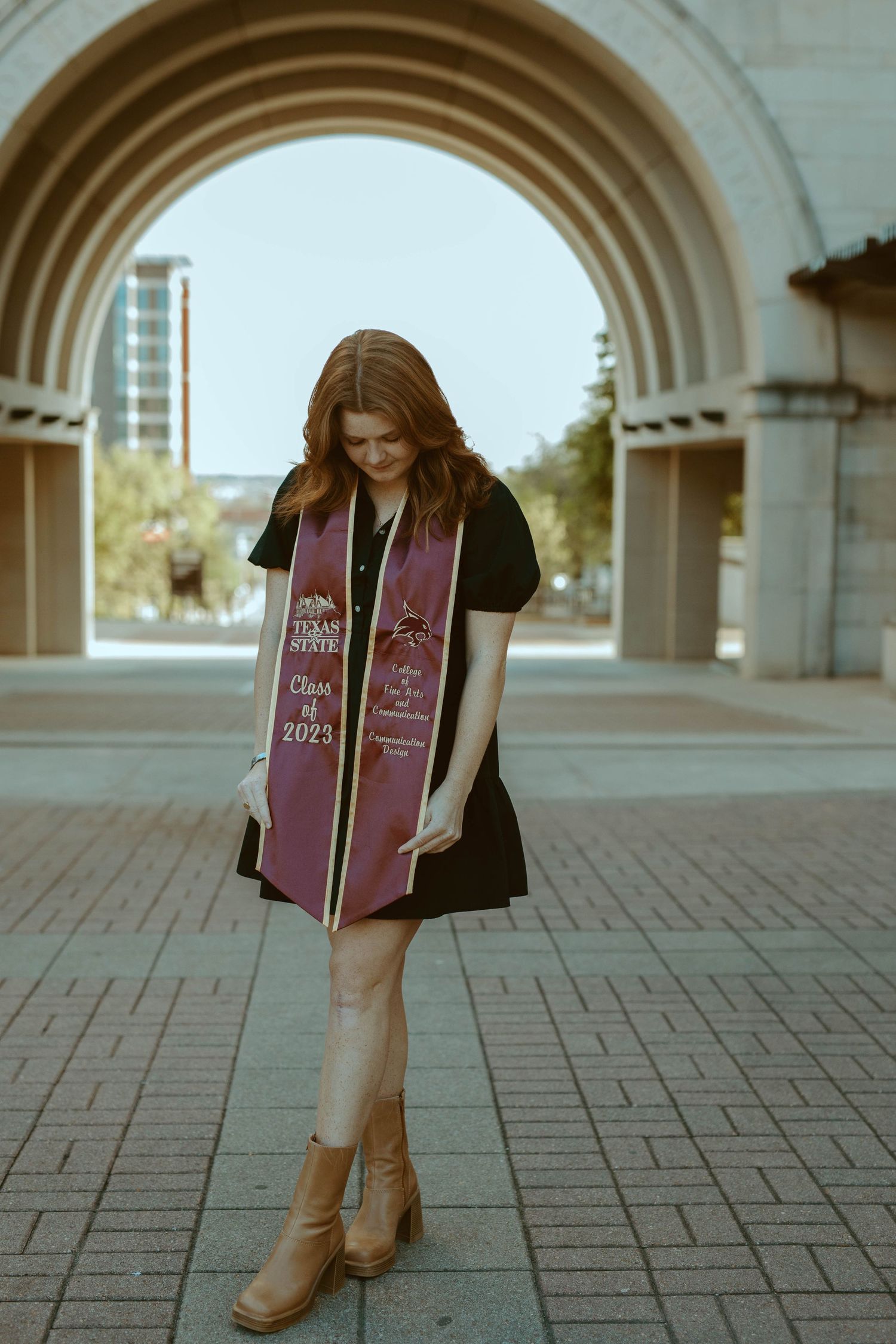 Texas State University graduate under the campus archway during a senior portrait session in San Marcos, TX.