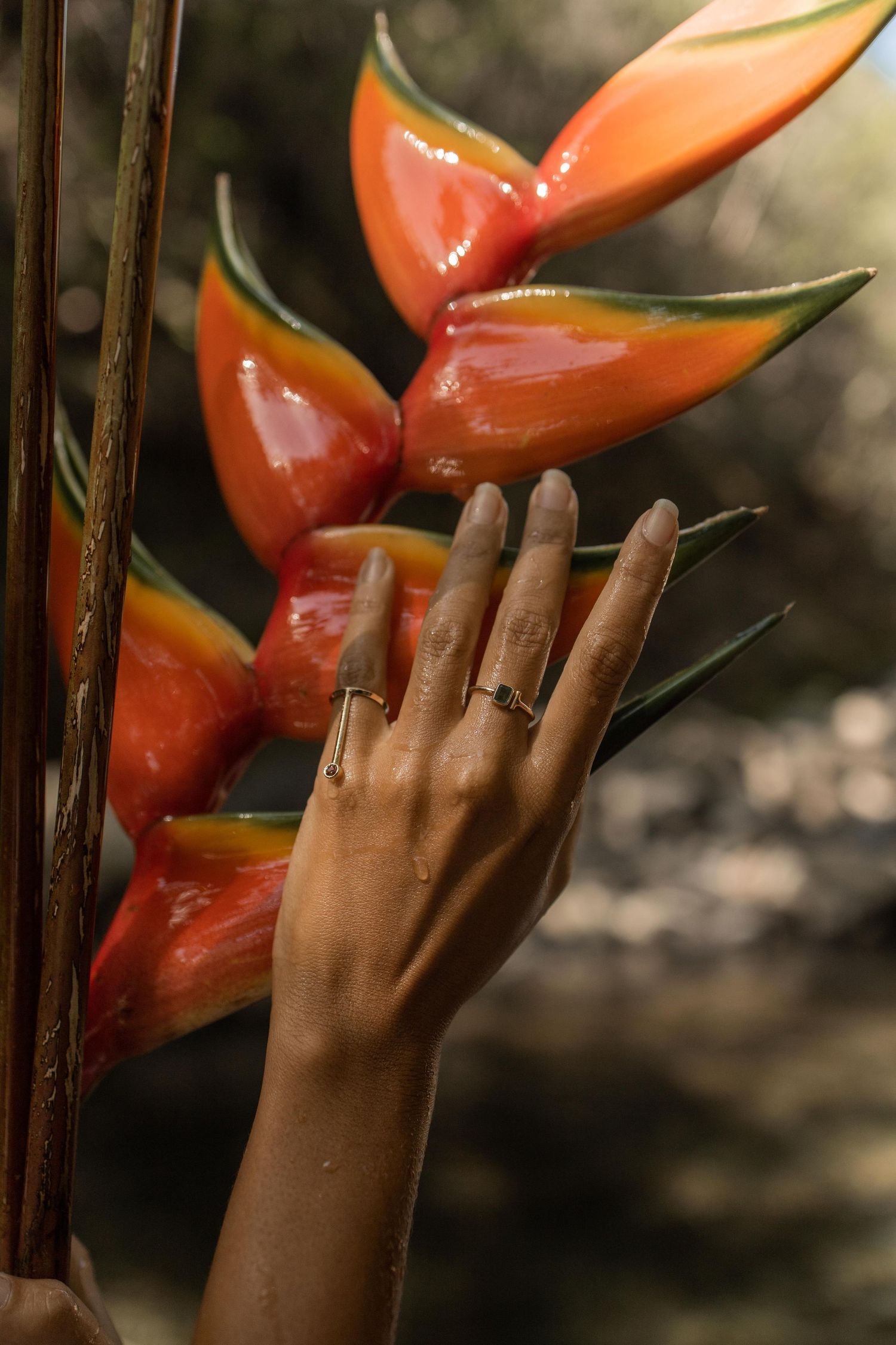 close up of woman's hand touching tropical flower wearing Maui made rings