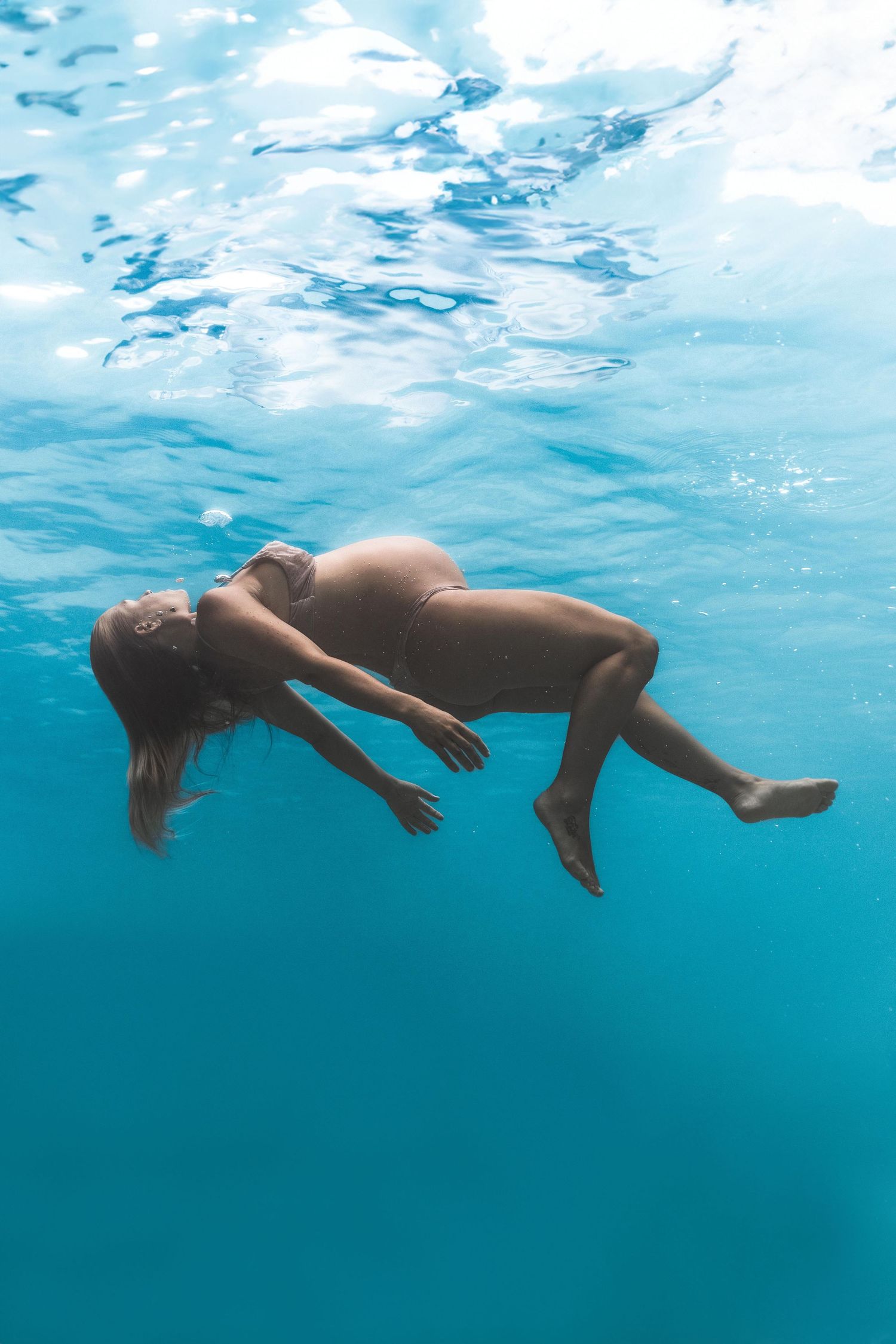 pregnant woman floating underwater on Maui