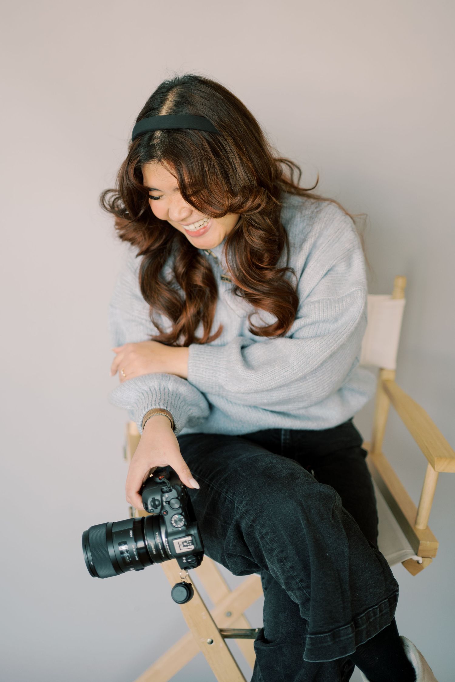 A photographer in a cozy grey sweater reviews images on their professional camera.