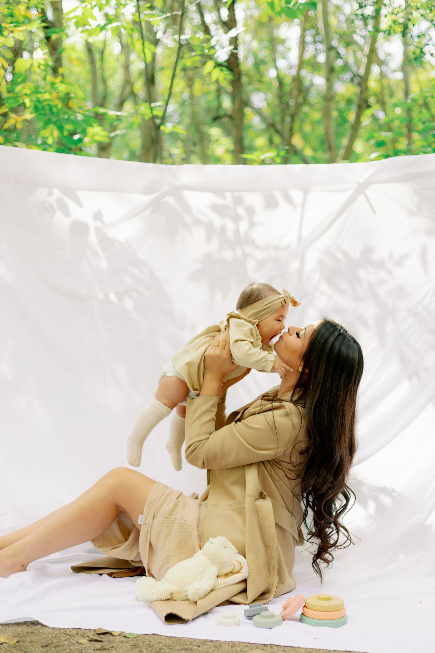 A tender moment on a white backdrop with warm neutral tones and natural lighting in an outdoor setting.