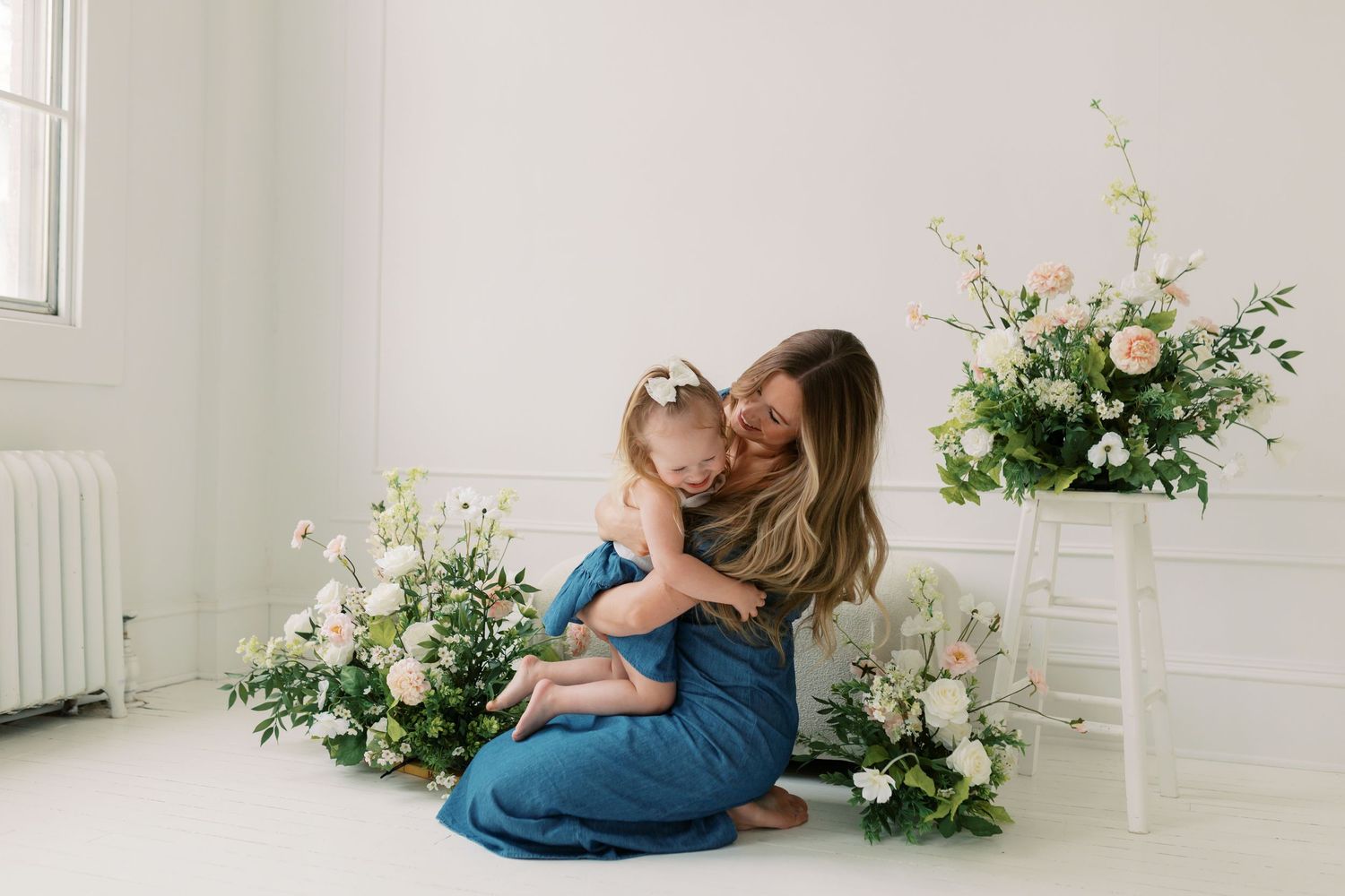 Elegant floral studio photography session with white backdrop and pink flower arrangements.