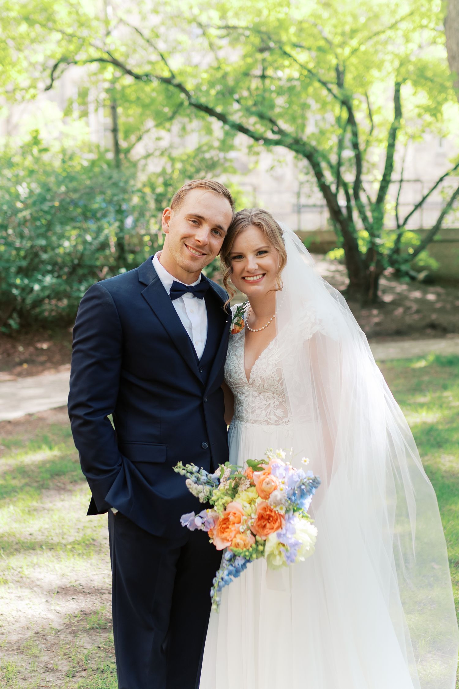 A bride and groom share a romantic moment in their wedding attire with colorful bouquet.