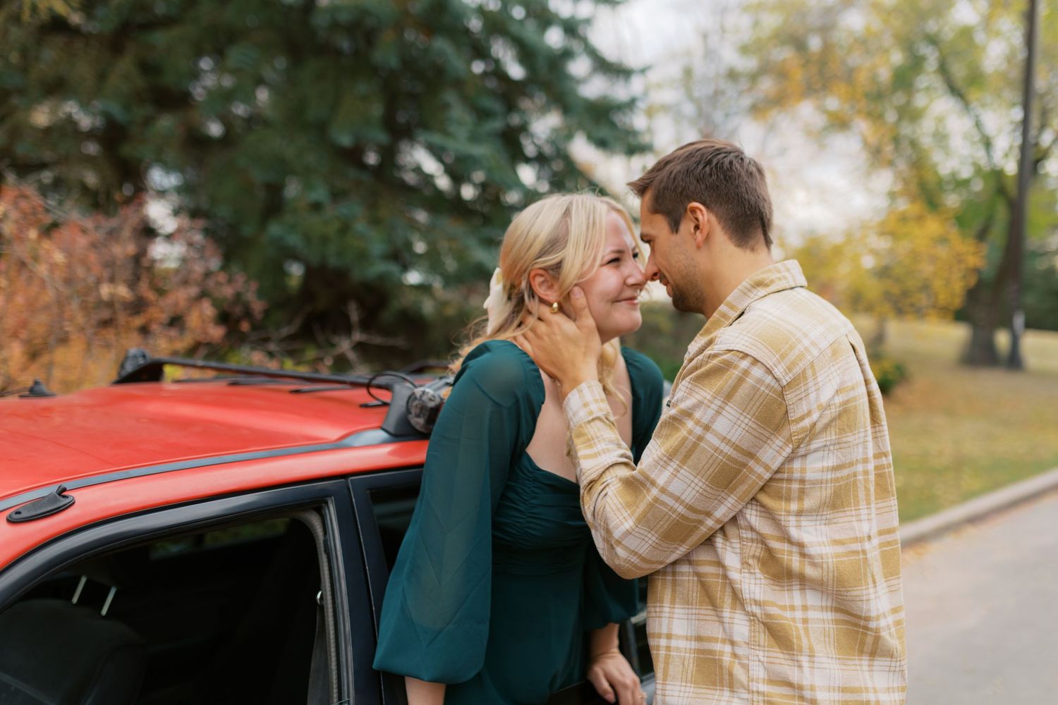 A couple shares romantic moments in a fall setting near a vintage red car in a series of connected photographs.