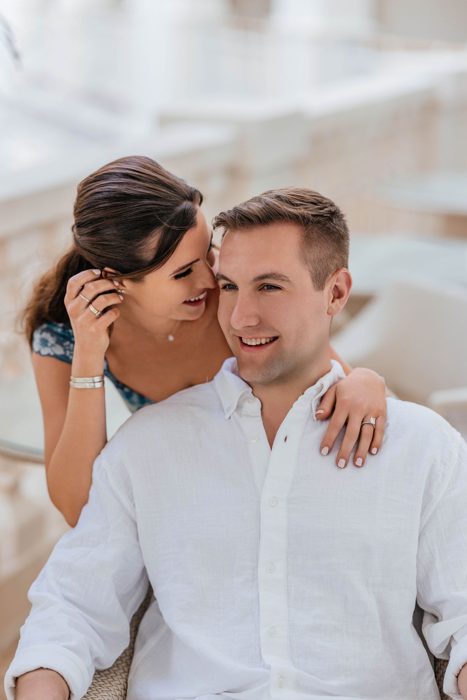 A romantic couple sharing an intimate moment outdoors wearing white and blue clothing.
