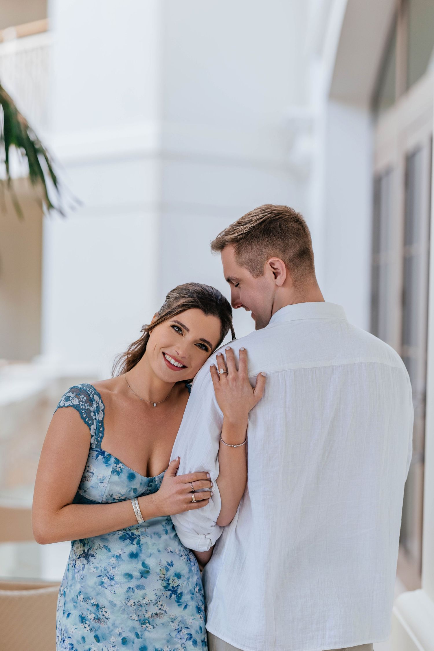 A couple embracing and laughing together against a white wall background.