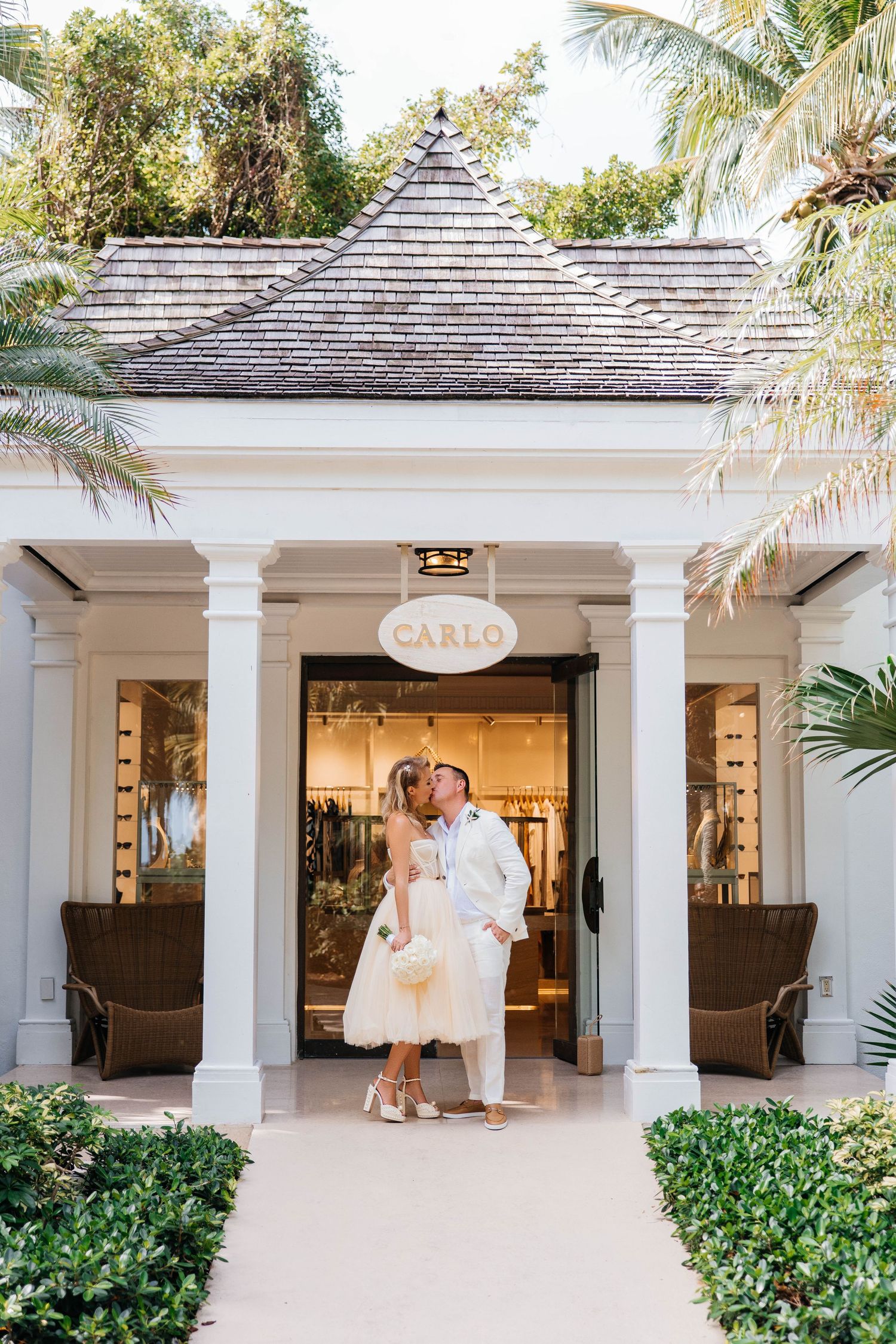 Elegant white gazebo entrance with tropical landscaping and palm trees at a luxury resort.