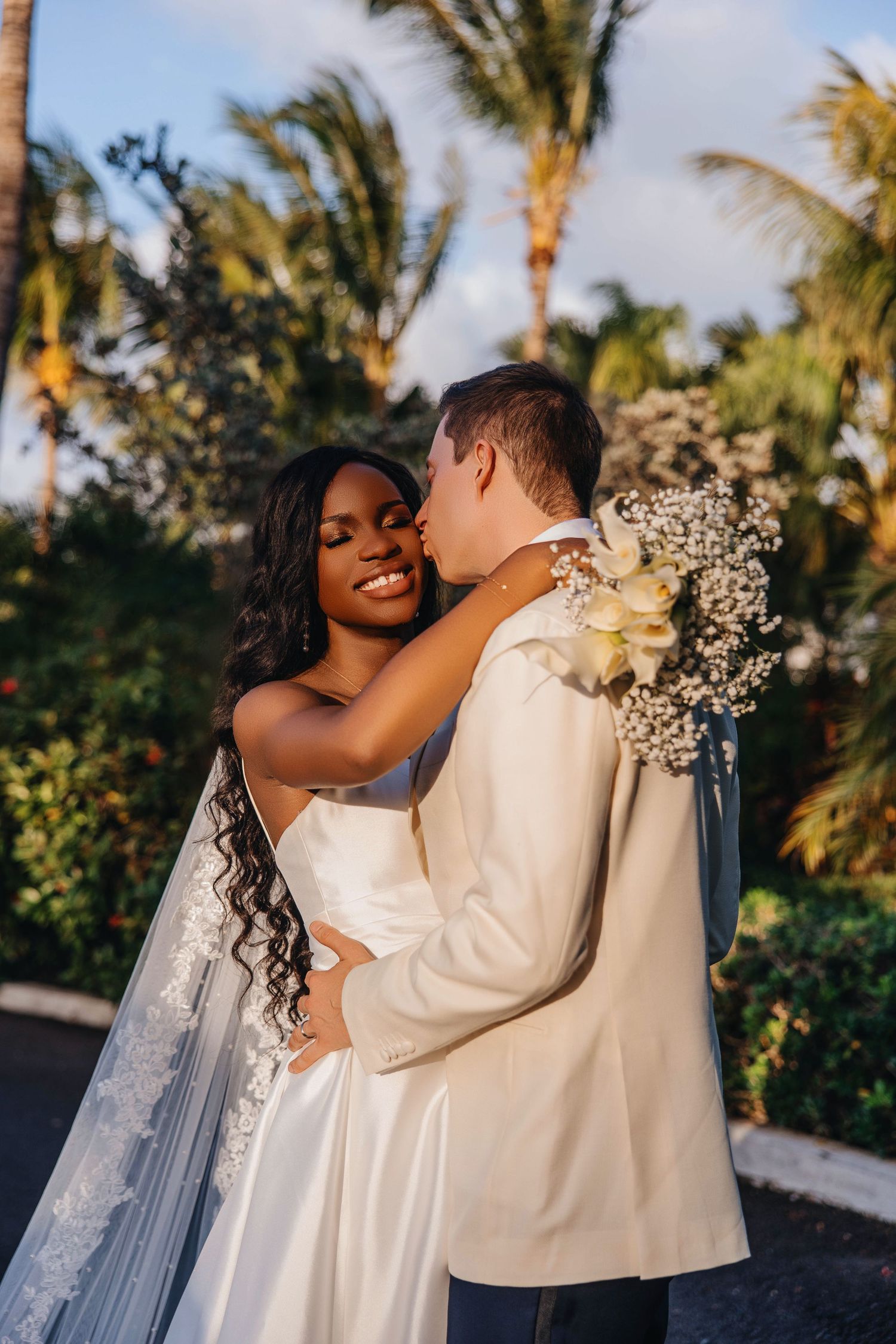 Intimate embrace between newlyweds with bride holding bouquet of baby's breath flowers.