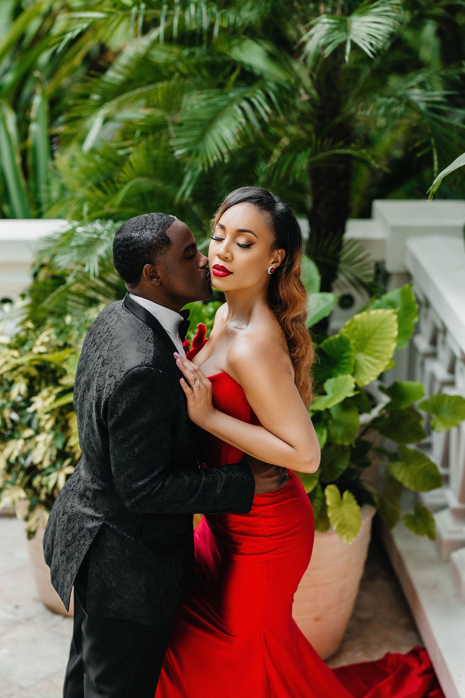 Romantic tropical garden photoshoot featuring formal attire against lush palm backdrop.