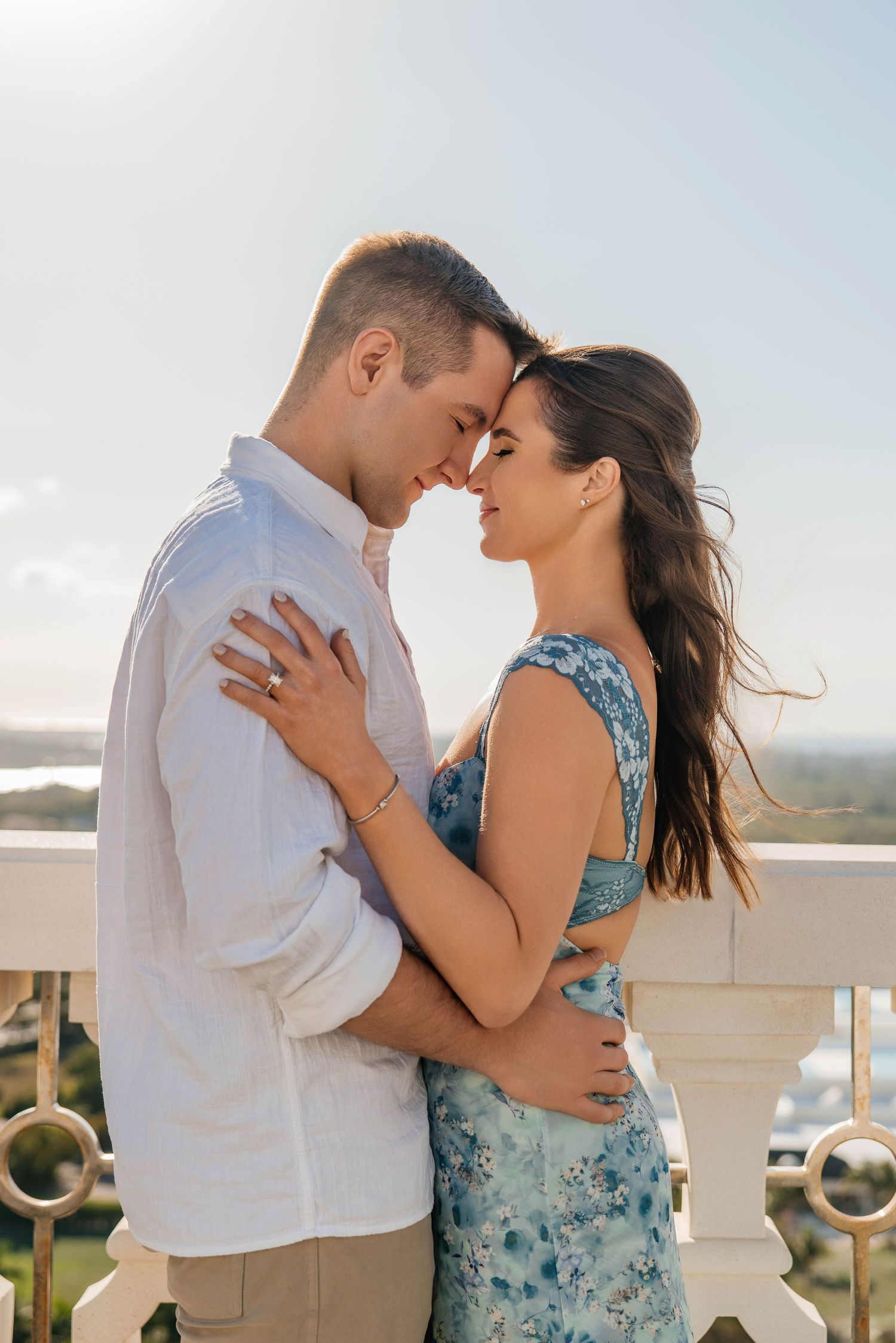 A romantic couple embracing on a balcony with a scenic view.