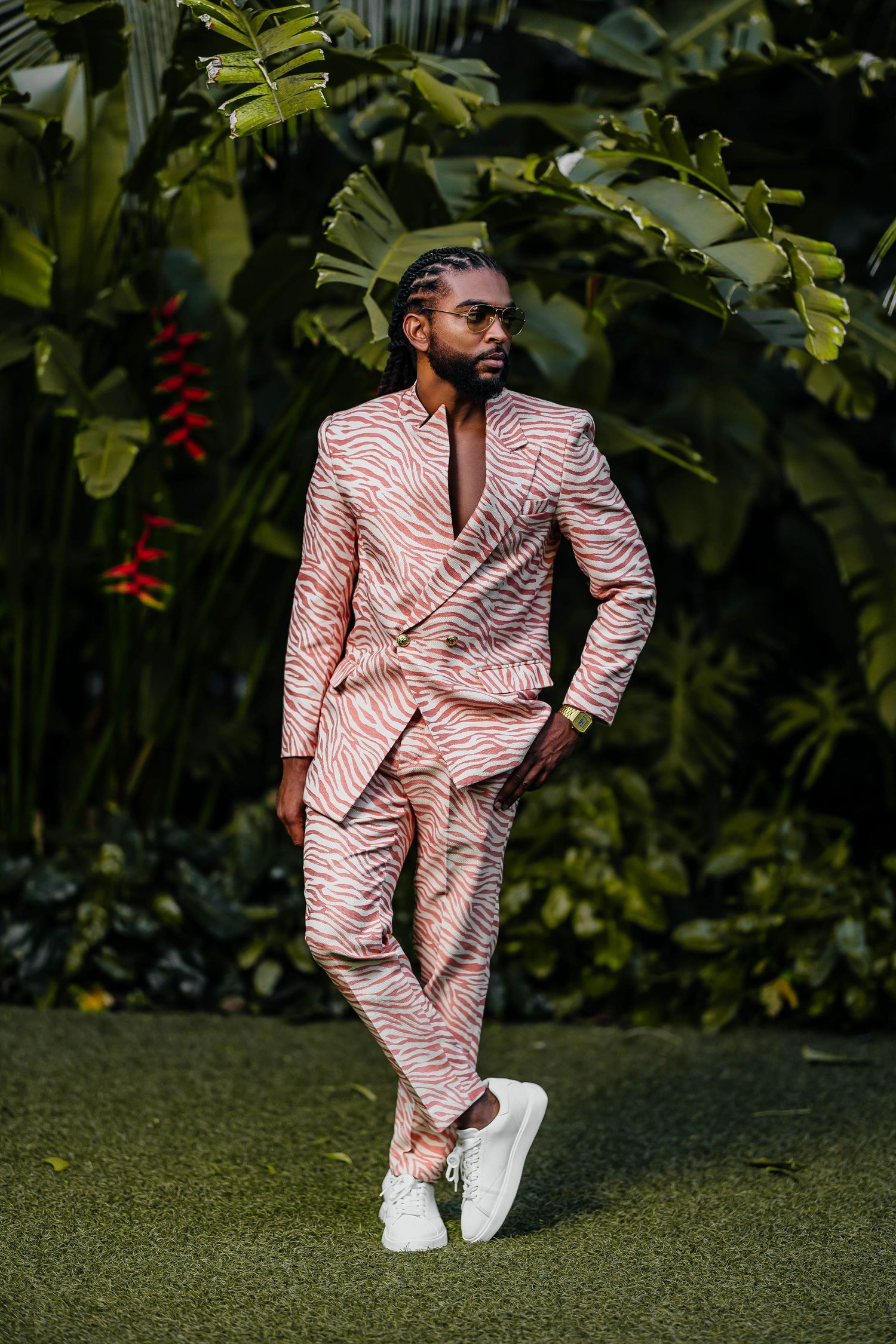 Stylish pose in pink textured suit against tropical garden background.