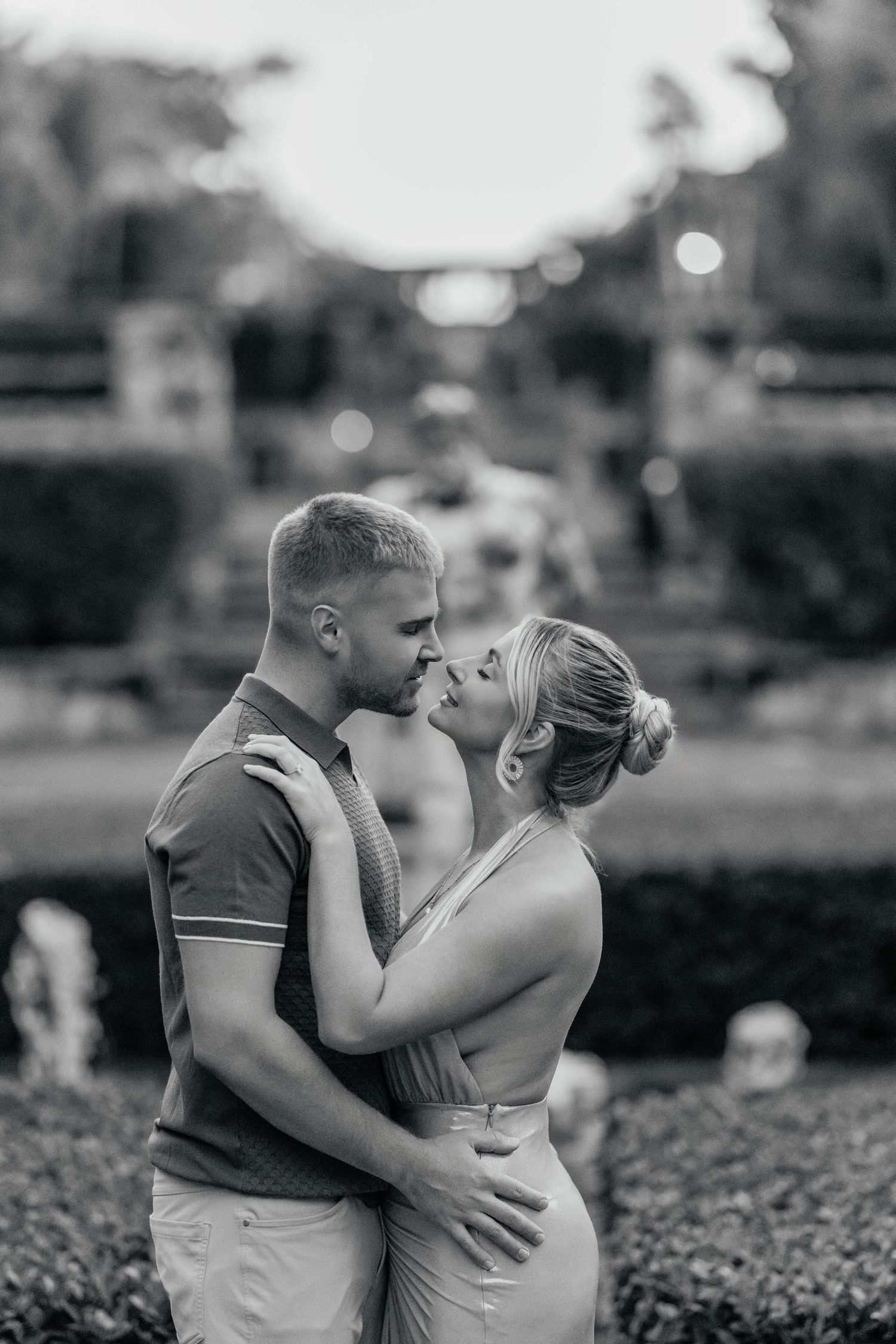 Romantic black and white portrait of couple embracing in a garden setting.
