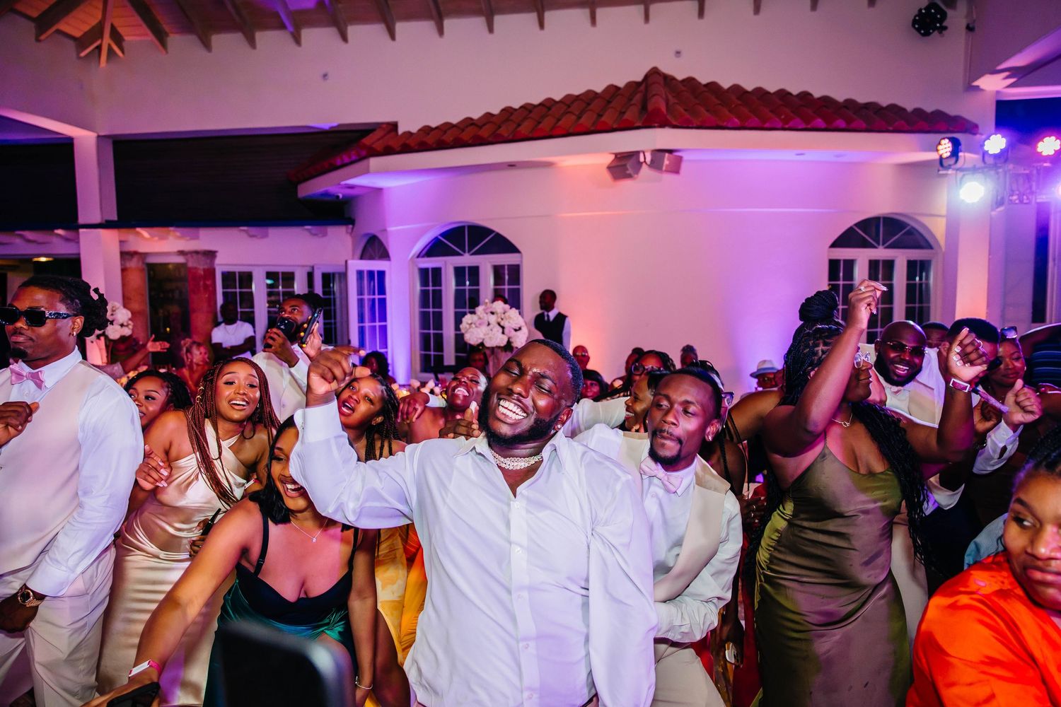 Crowd of guests dancing and celebrating joyfully at an elegant wedding reception.