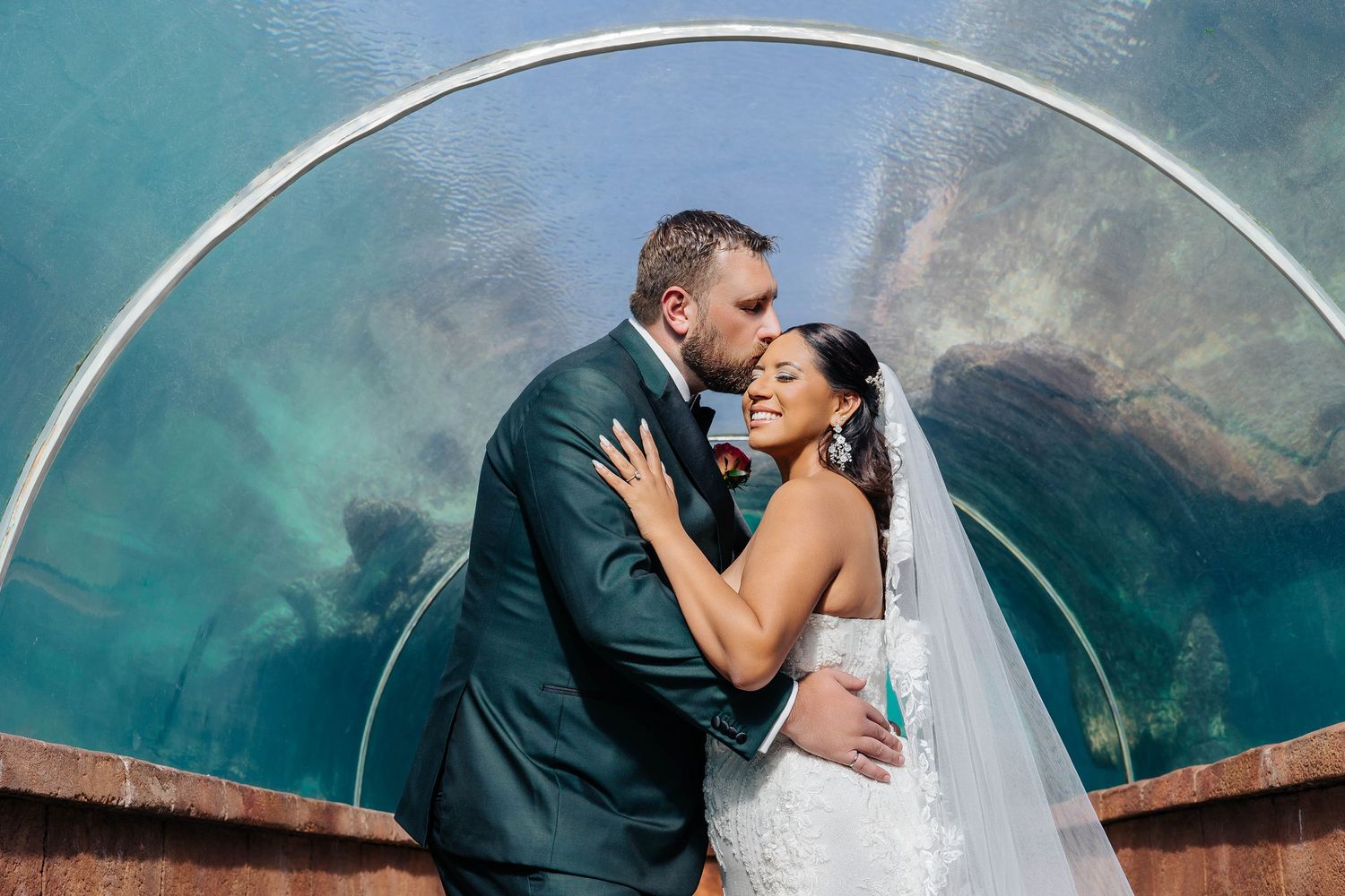 Intimate moment captured in an underwater viewing tunnel with aqua blue surroundings.