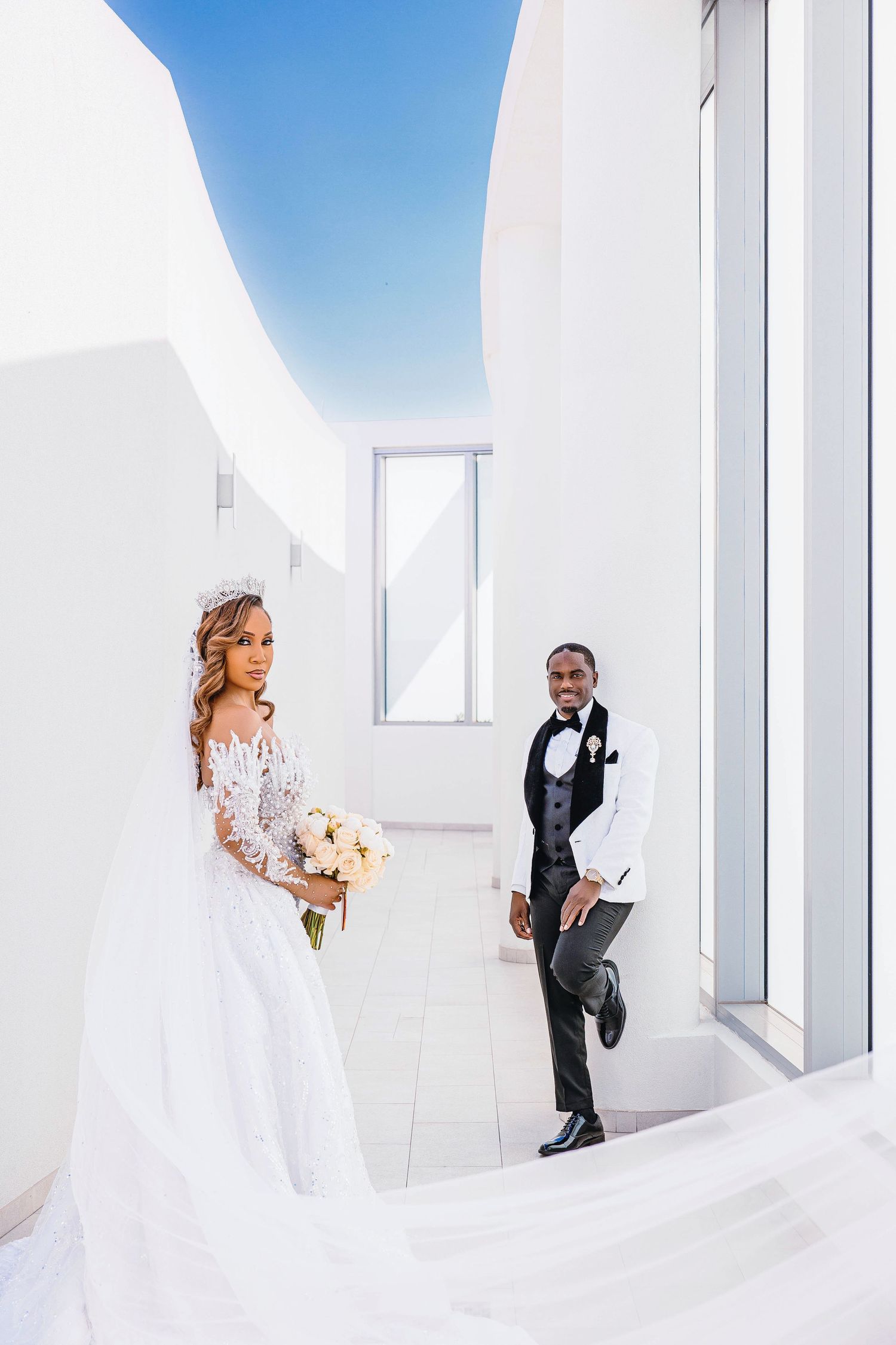 Playful wedding photo shoot in contemporary white corridor with dramatic architectural lines.