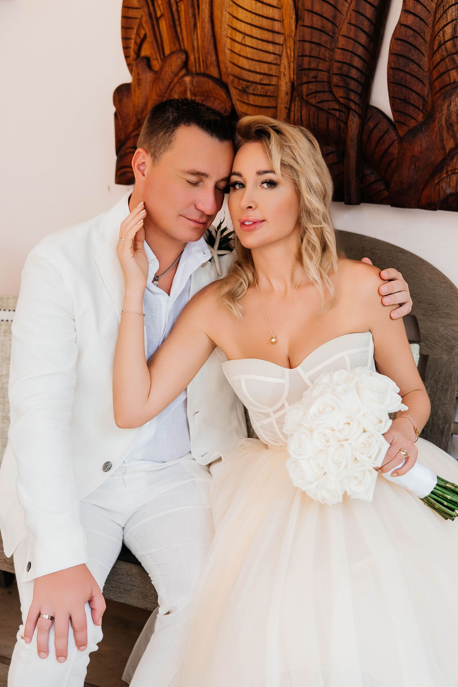 An elegant wedding portrait featuring a couple against a decorative wooden wall.