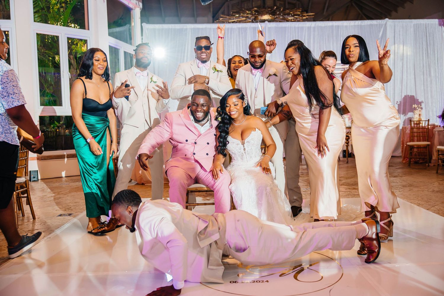 Wedding party posing with bride and groom in a fun group photo on the dance floor at a reception.