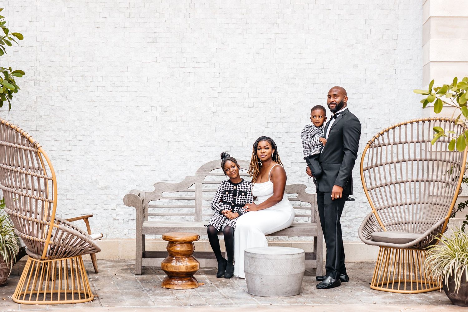 Modern family portrait on elegant patio featuring rattan chairs and minimalist decor.