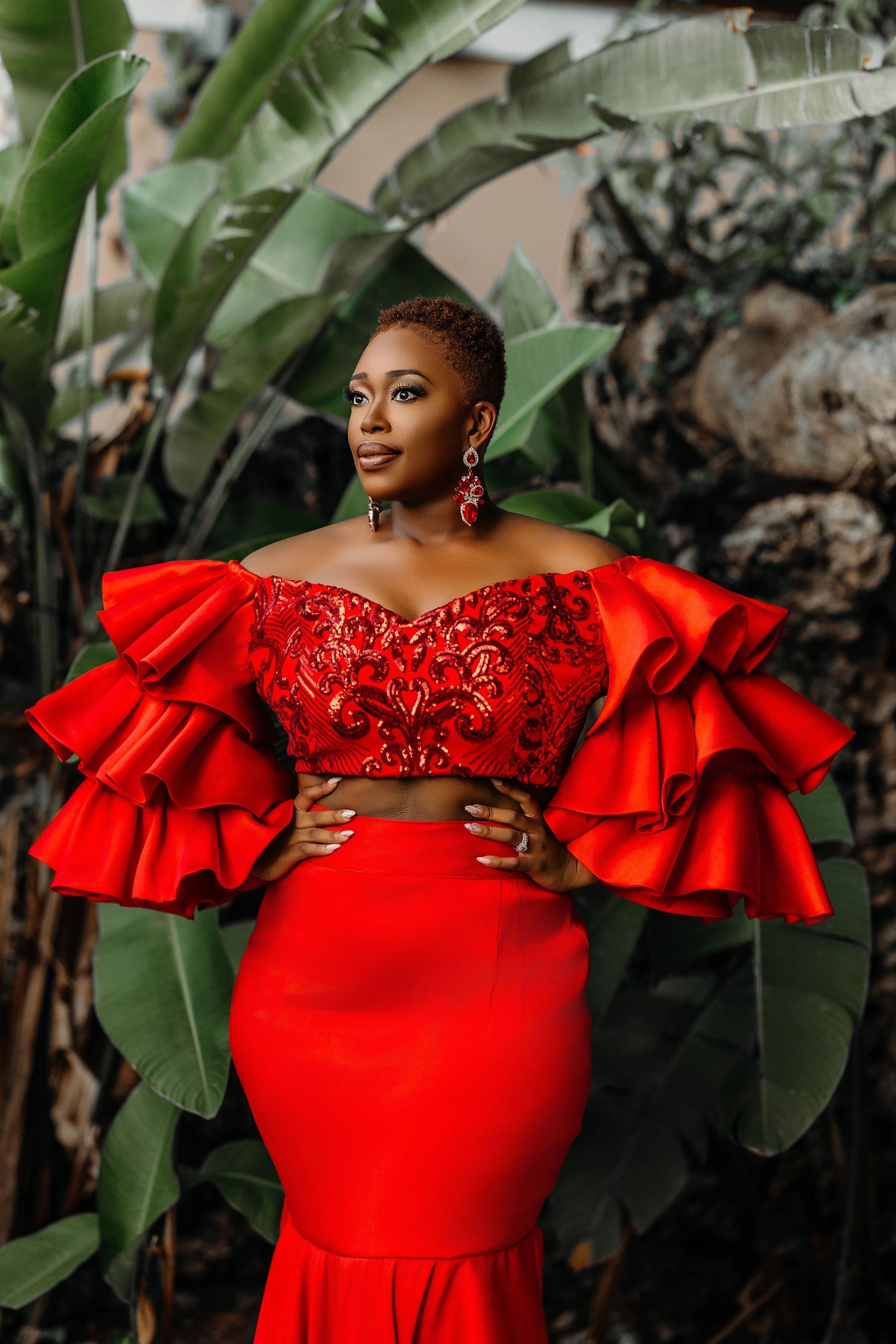 Fashion portrait in tropical setting featuring dramatic red ruffled formal gown.