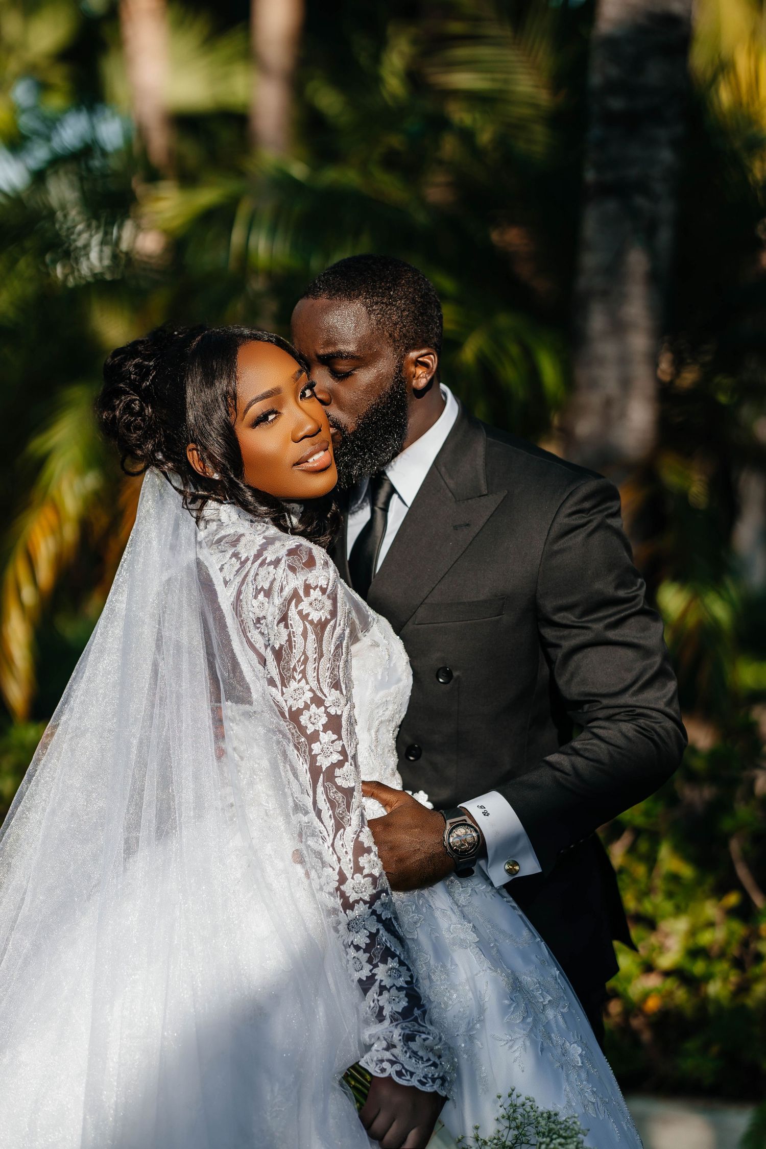 A candid wedding moment showing pure joy and love in a tropical garden setting.