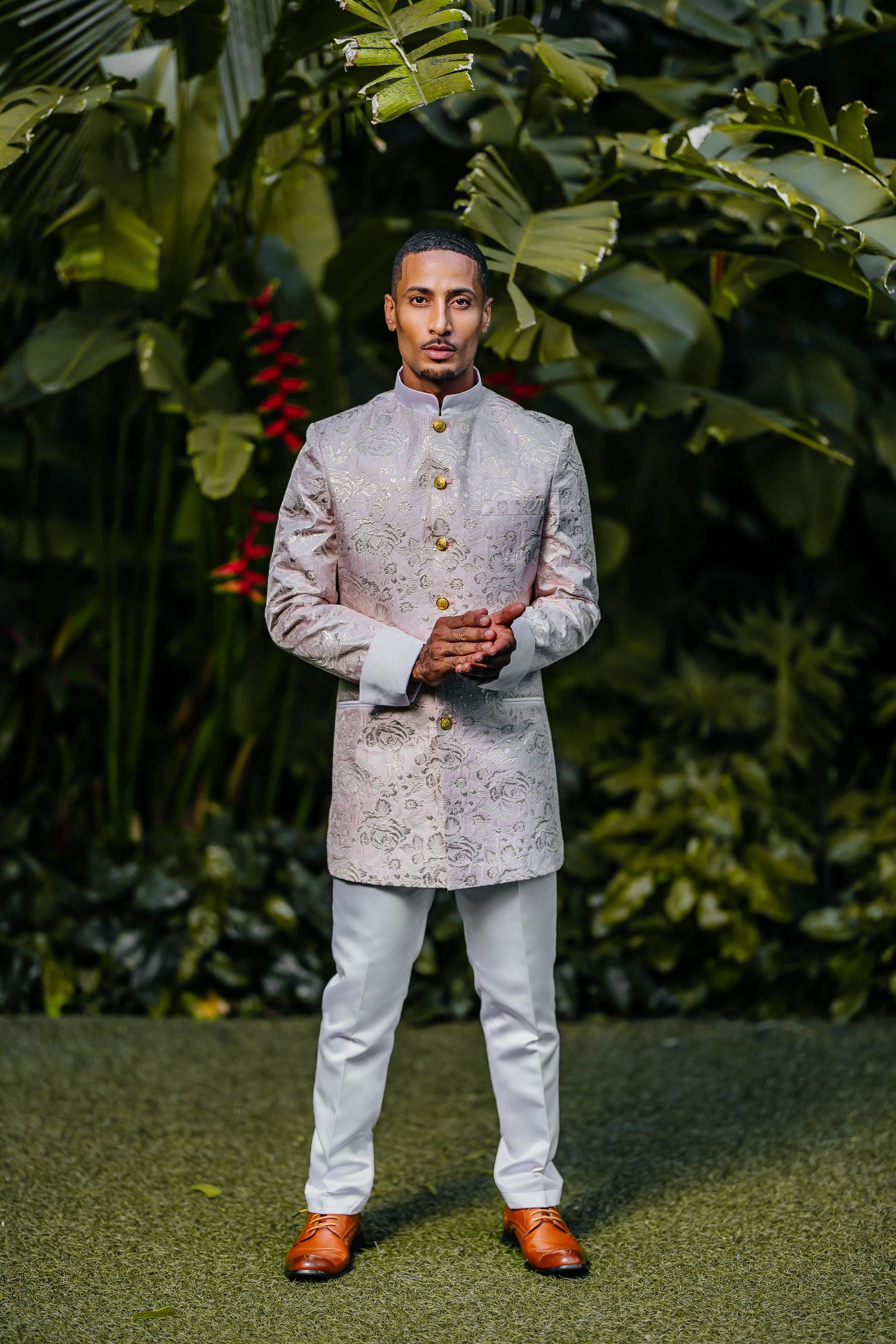 Stylish grey Nehru jacket and white pants outfit photographed against tropical foliage backdrop.
