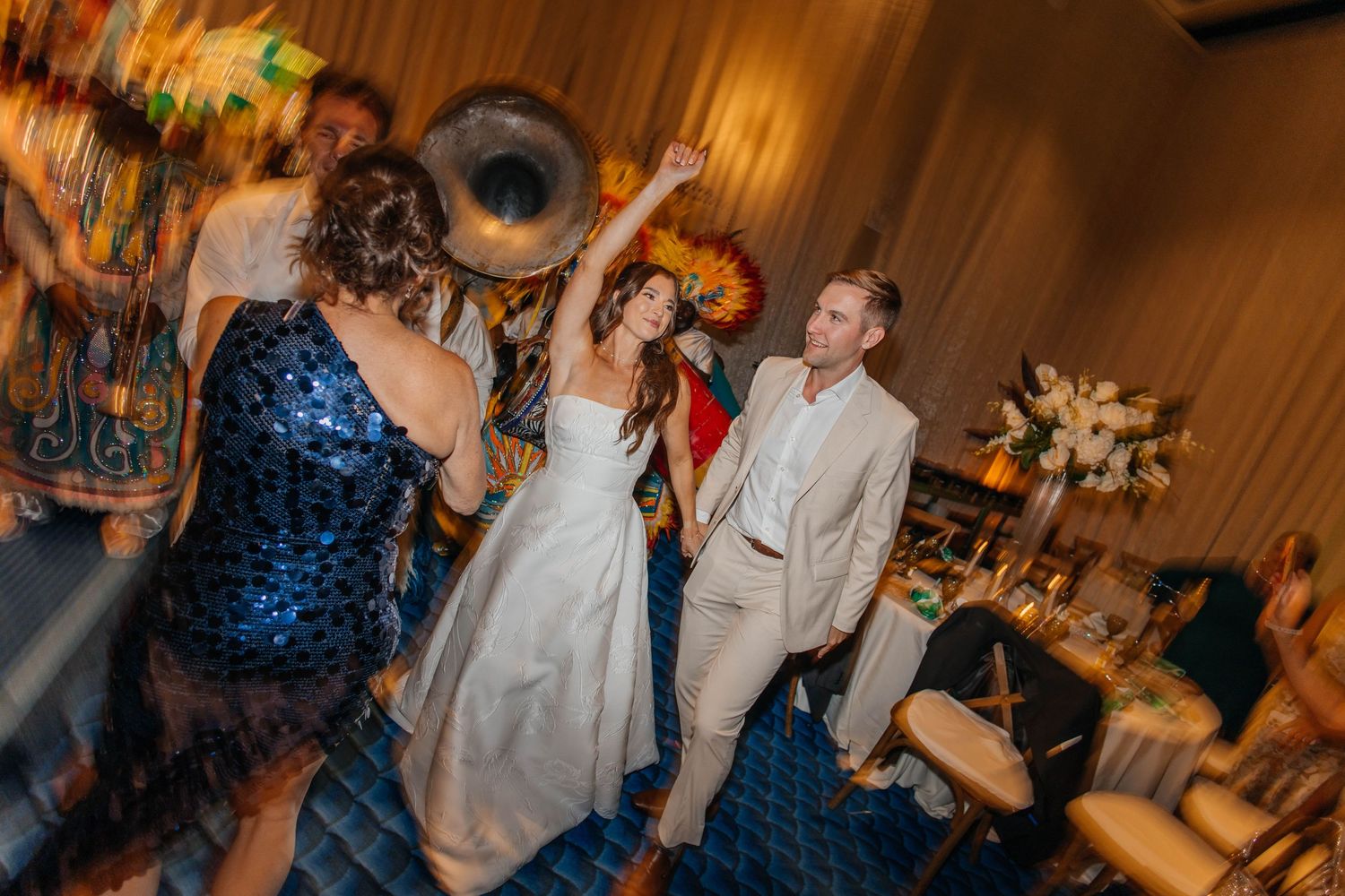 Bride and groom dancing joyfully at wedding reception with live brass band and guests celebrating.