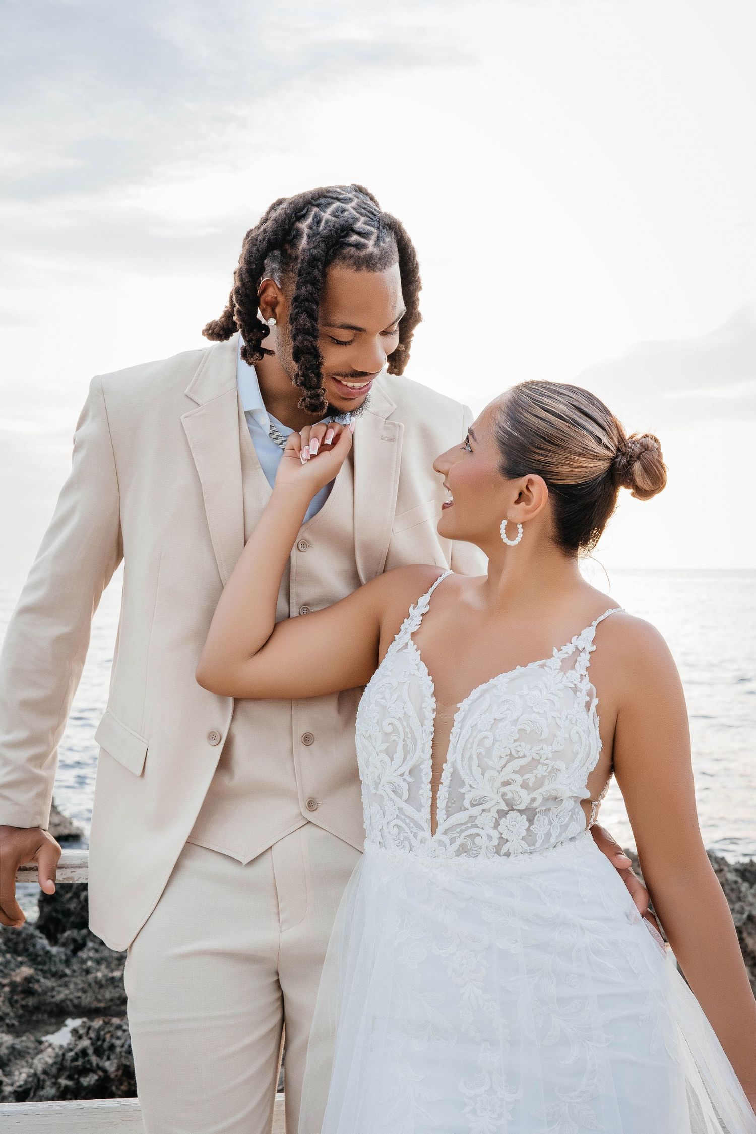 Intimate moment between newlyweds laughing together against ocean backdrop.