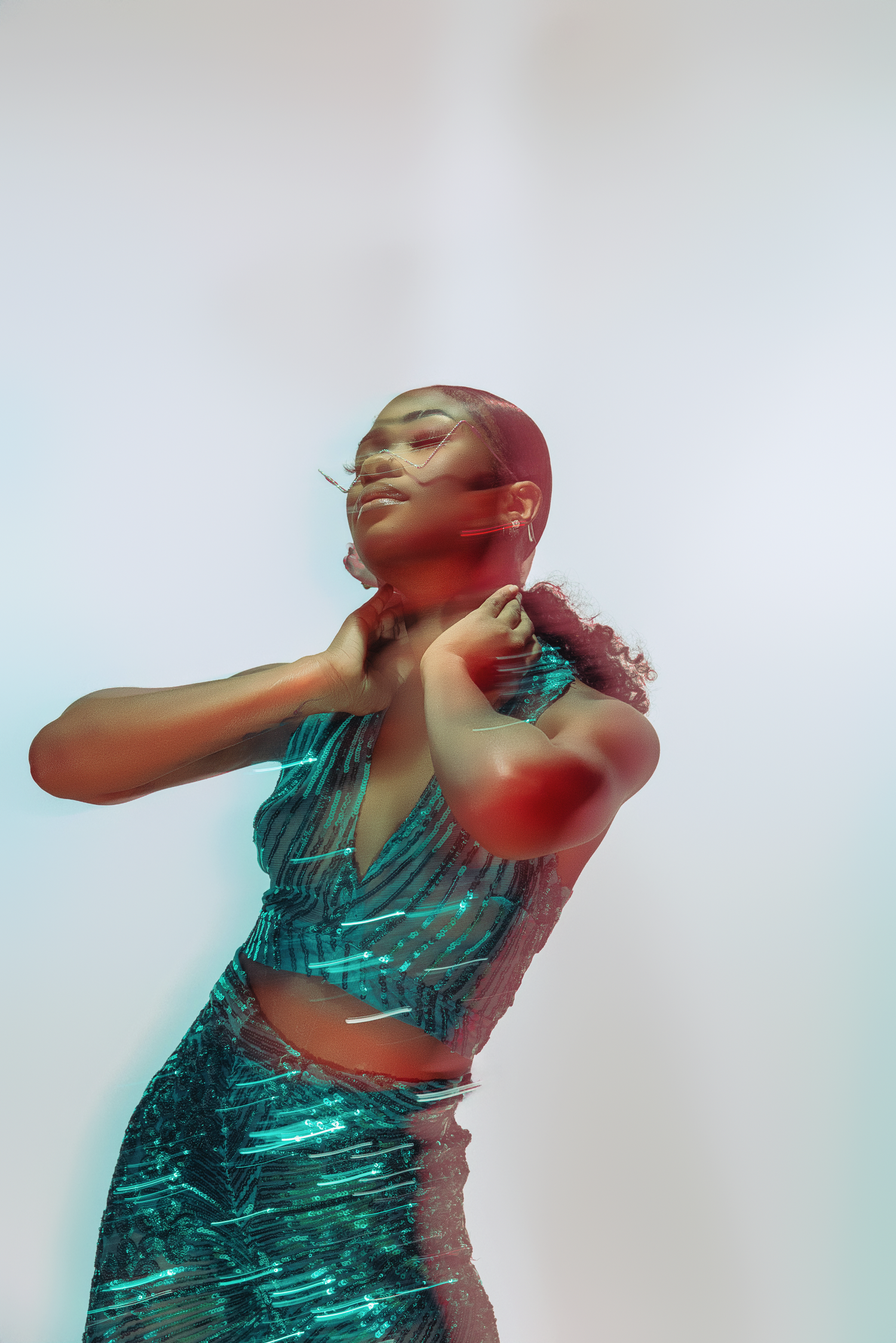 Fashion model in metallic green outfit poses dramatically with artistic lighting effects.