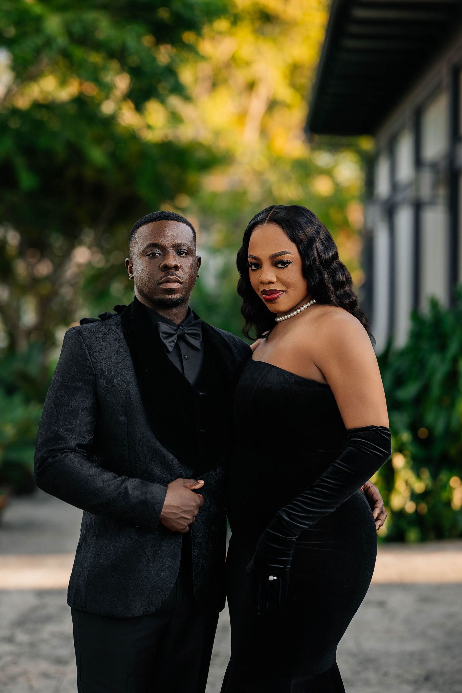 A romantic couple in elegant black attire poses together during an outdoor photo session at The Island House.