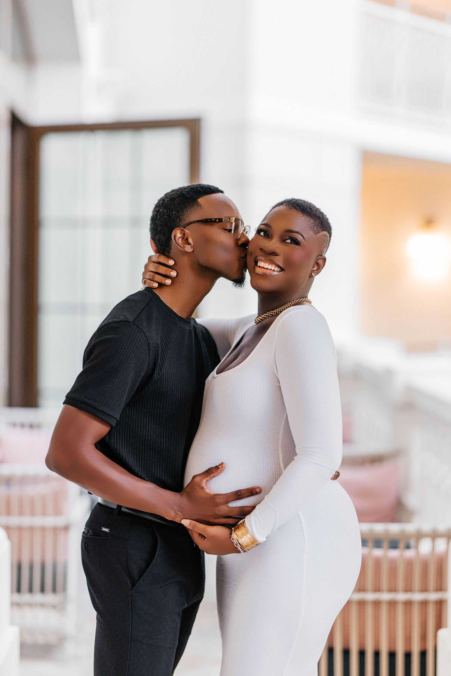 A couple embraces tenderly in white and black outfits during a maternity photoshoot.