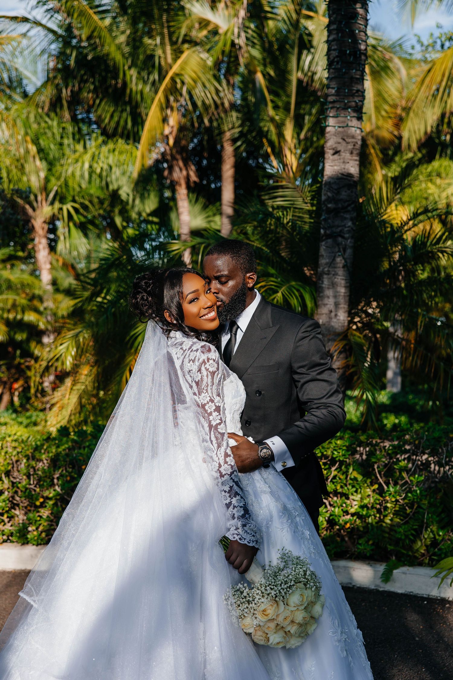 A joyful wedding moment between newlyweds surrounded by tropical palm trees.
