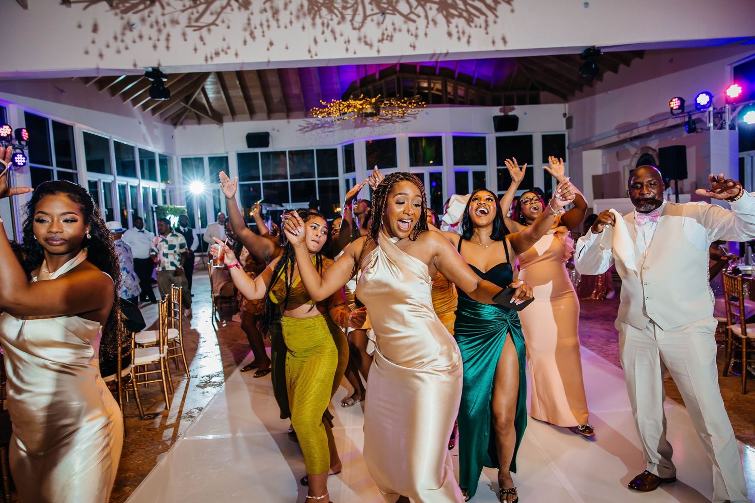 Joyful wedding guests dancing and celebrating on the dance floor at an elegant indoor wedding reception.
