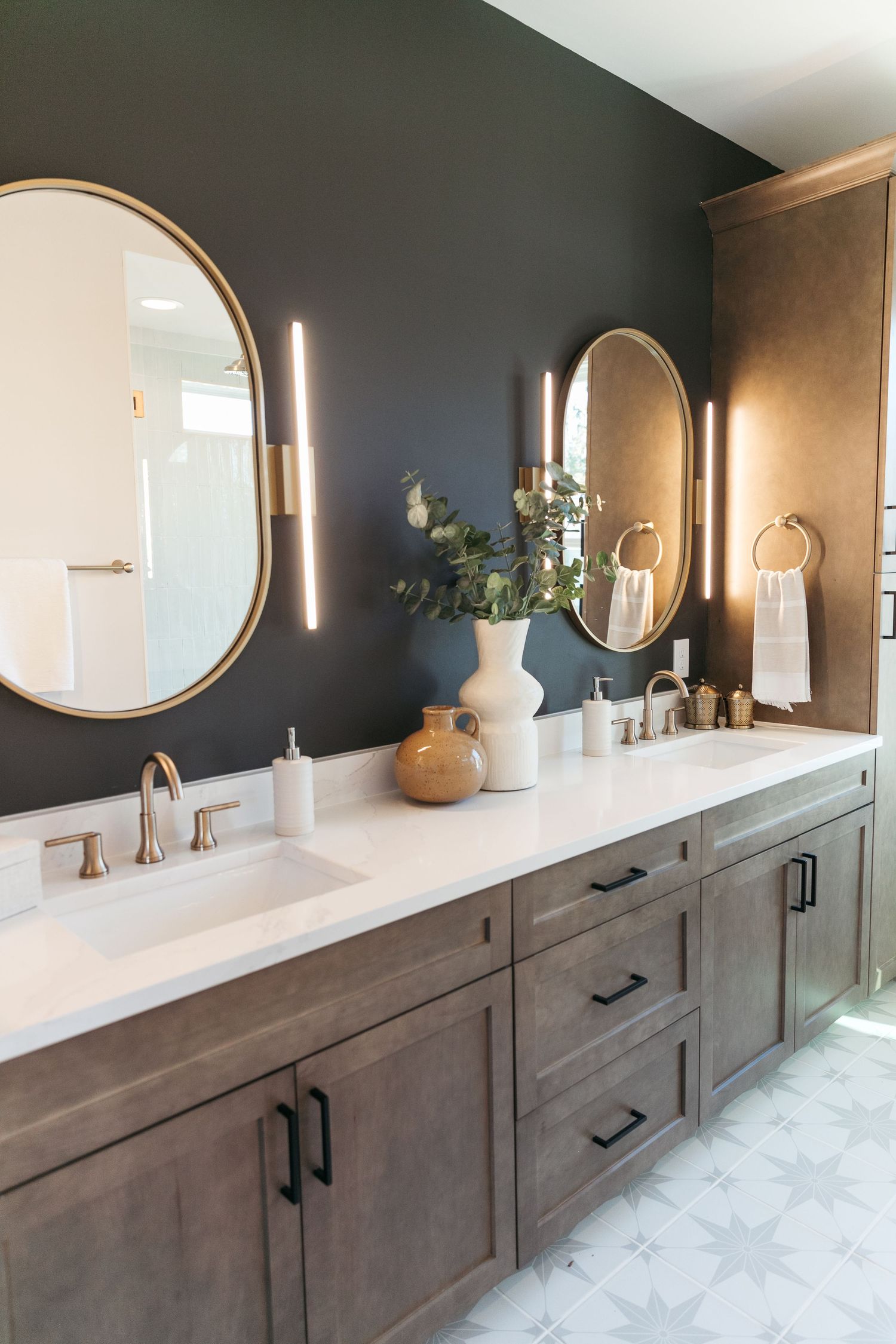 Luxurious bathroom vanity with dark accent wall and multiple circular mirrors above wooden cabinetry.