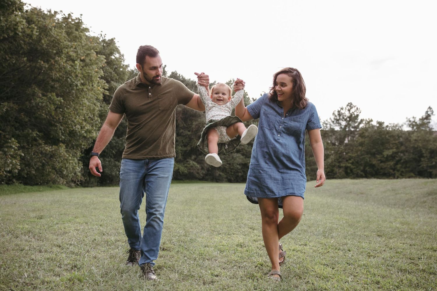 Happy couple running and playing in a grassy meadow during golden hour.