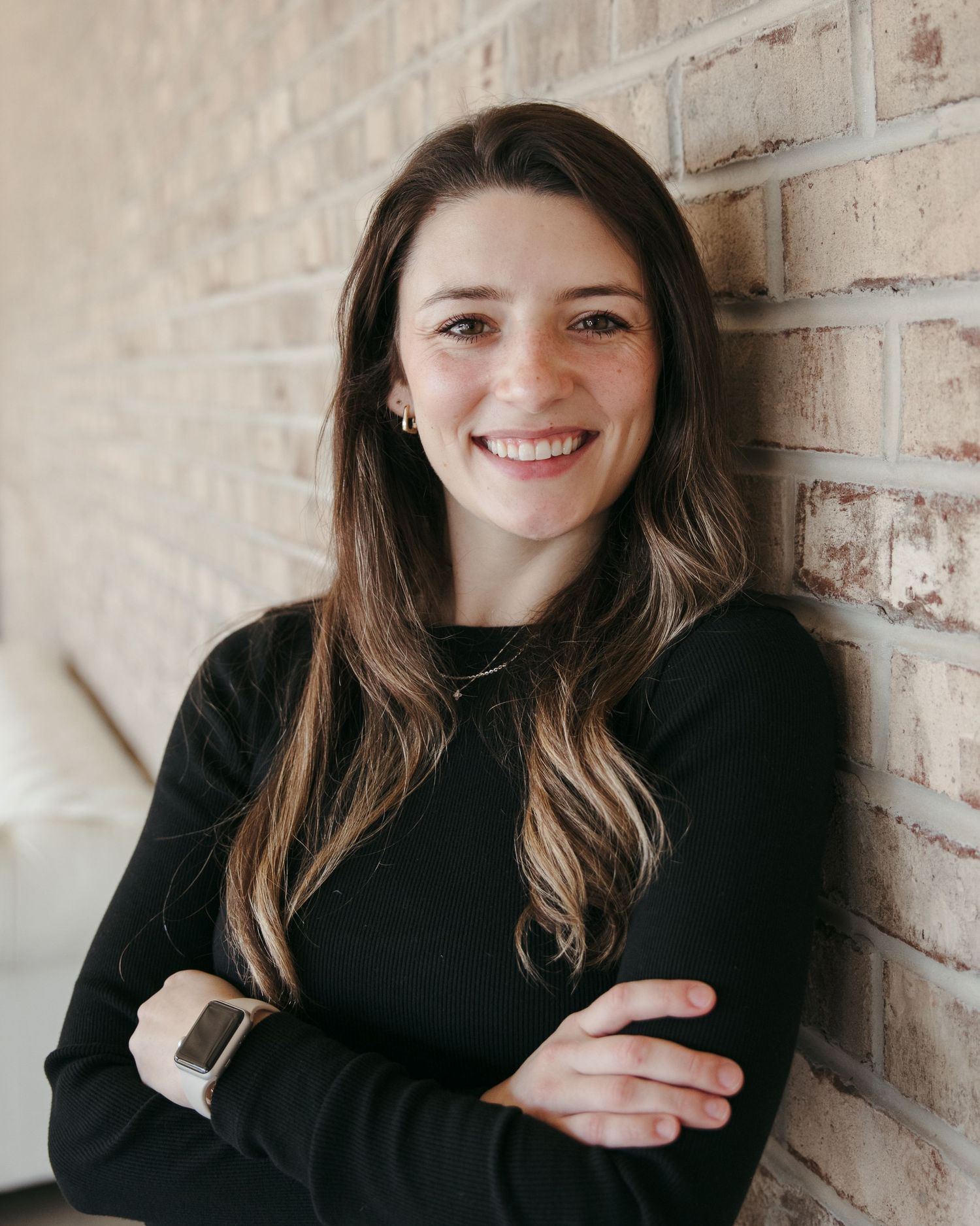 Portrait series of person in black sweater against light brick wall.