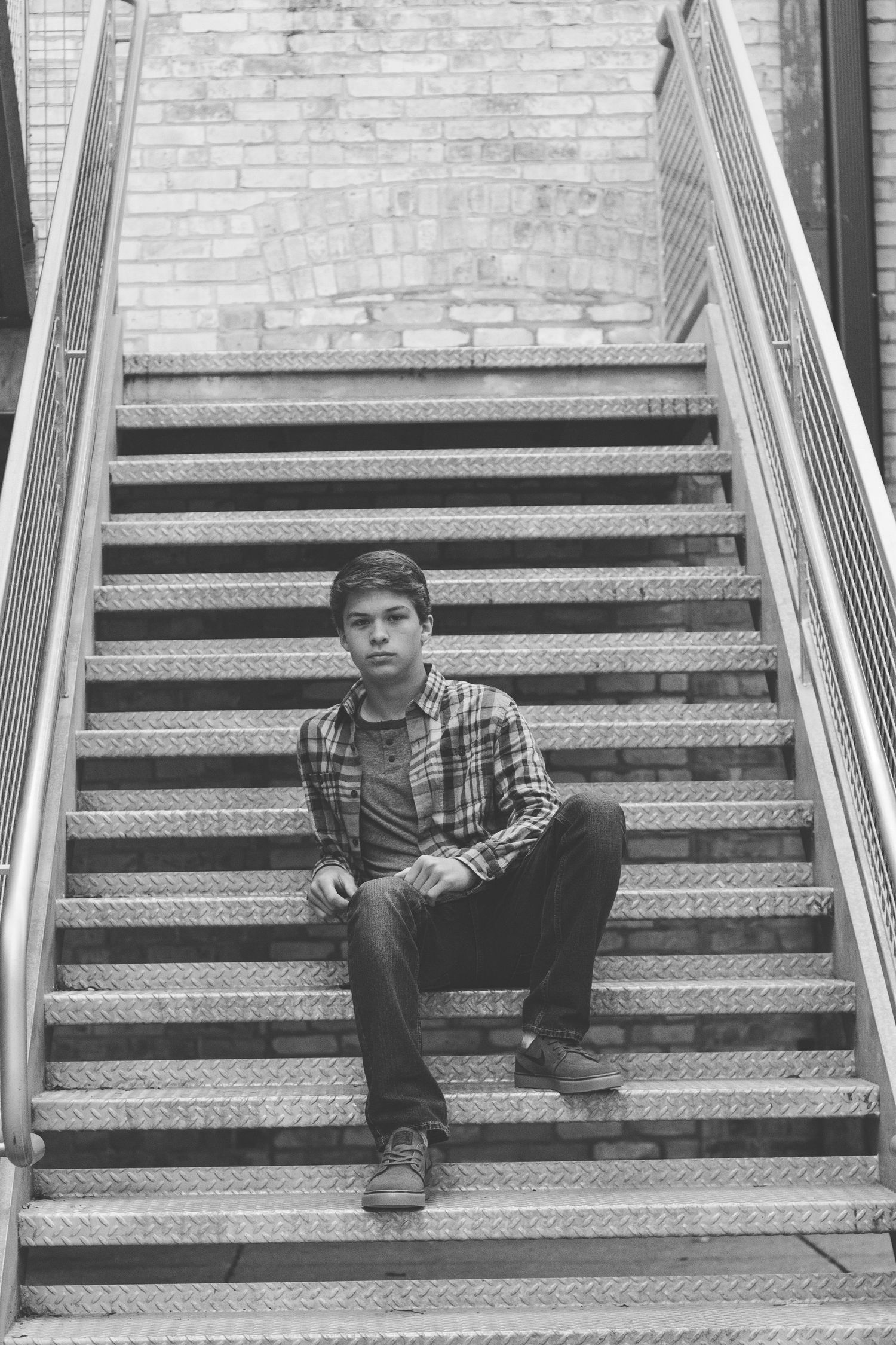 Black and white architectural portrait on metal stairs with industrial aesthetic.